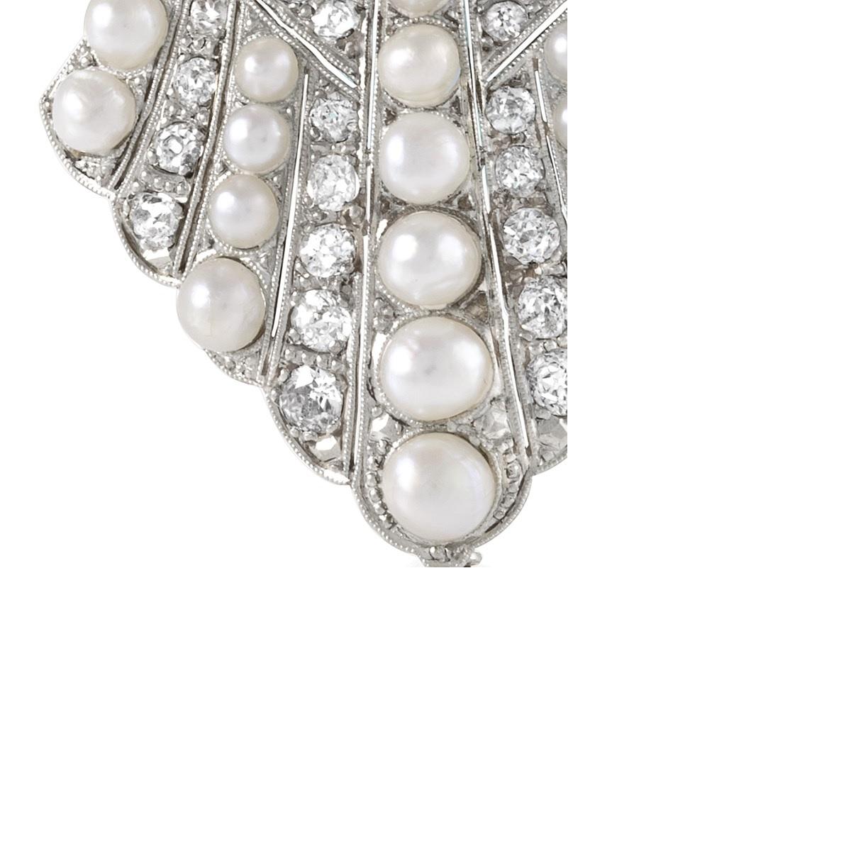 An Art Deco brooch in platinum with diamonds and pearls. The brooch has 54 Old European- and rose-cut diamonds with an approximate total weight of 3.2 carats and a large center old mine-cut stone with an approximate total weight of 1.25 carats. The