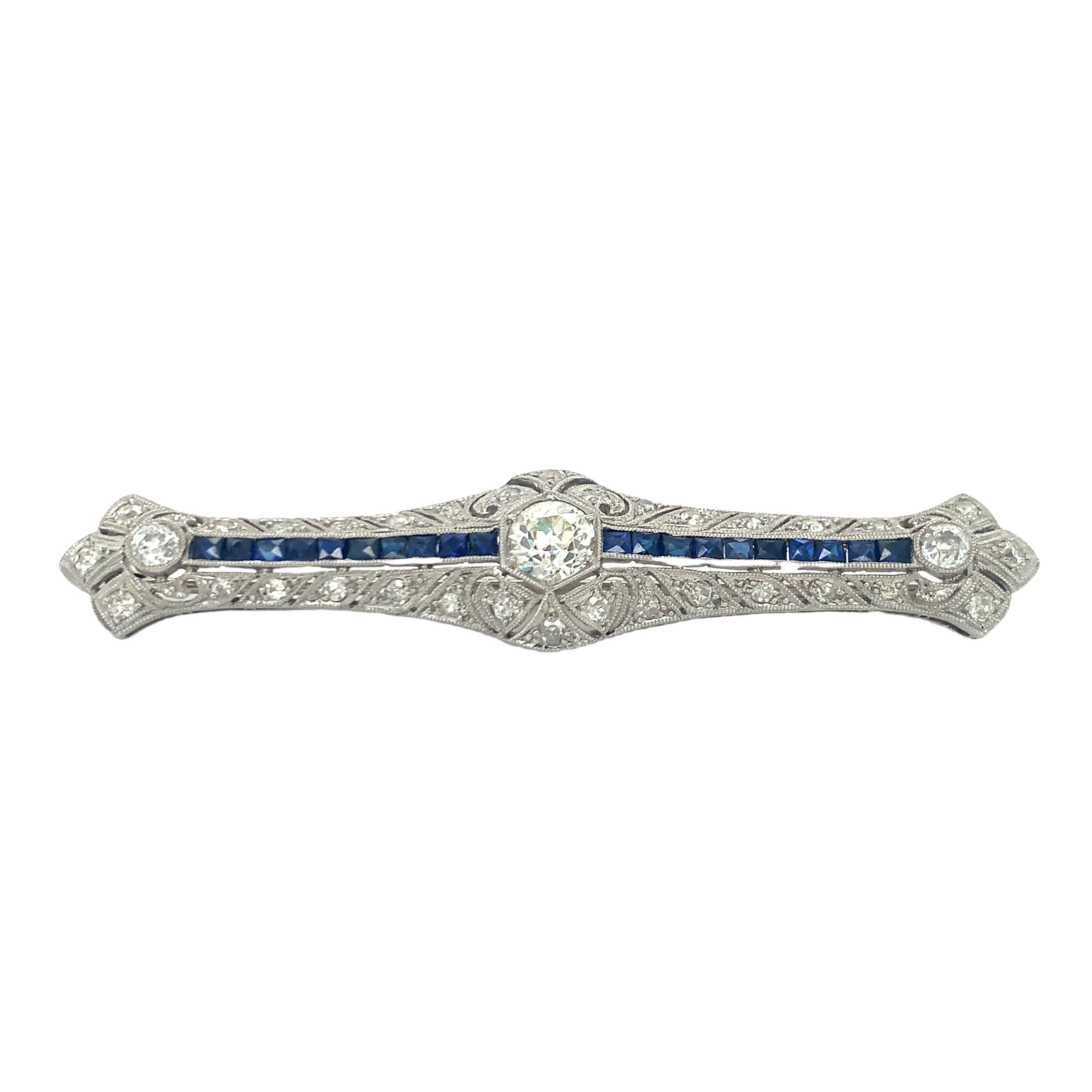 Une broche Art déco réalisée dans une monture filigrane en platine, mettant en valeur un diamant de taille européenne ancienne pesant environ 1,05 carats de couleur K-L et de pureté SI. Le motif est également rehaussé par vingt saphirs de taille
