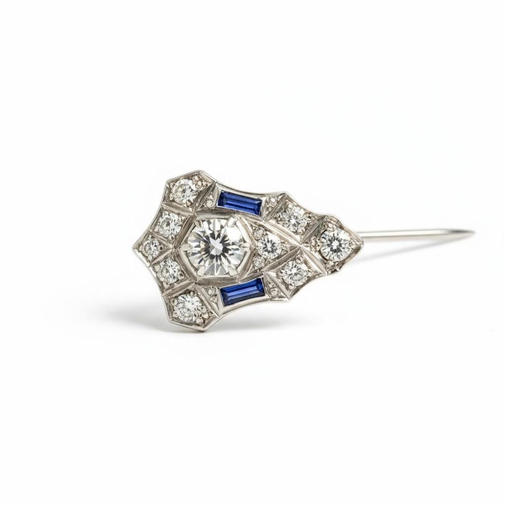 Este alfiler de gancho de platino, un sorprendente ejemplo del refinamiento Art Decó de los años 20, muestra una combinación bellamente equilibrada de diamantes y zafiros en un diseño que personifica la simetría geométrica y el encanto intemporal de