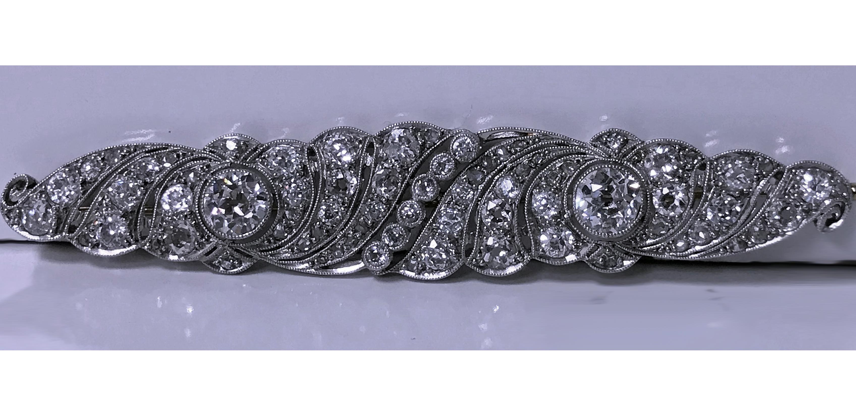 Art Deco Platinum Diamond bar Brooch, C.1920. The brooch bezel milligrain diamond set with two old european cut diamonds, diamond weight approximately 0.97ct and 0.87 ct respectively, with pierced swirl milligrain set surround of 72 mixed old cut