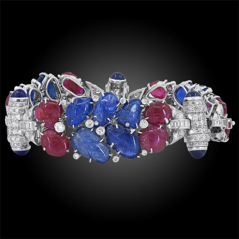 Art deco platinum bracelet, set with carved sapphires, ruby and old European-cut diamonds weighing approx. 7 cts., circa 1935.
Total length approx. 7 1/2″ x 7/8″