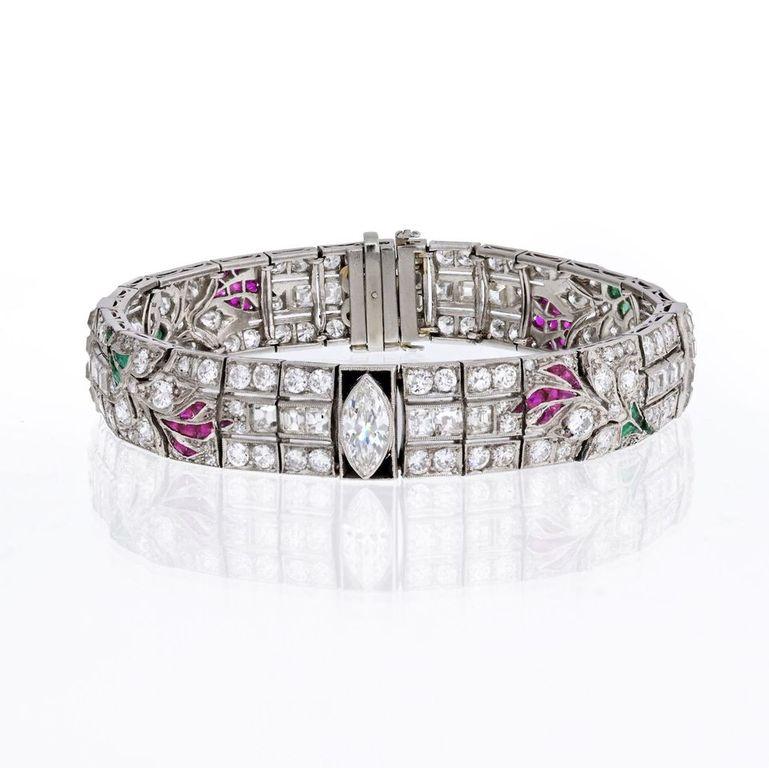 Dies ist ein elegantes Armband aus Platin mit Diamanten, Smaragden, Rubinen und Onyxen aus der Zeit des Art déco. Das Armband ist mit einem funkelnden Marquise-Mittelstein und runden Brillanten besetzt, die etwa 2,00ct bzw. 11,00ct wiegen. 
Die