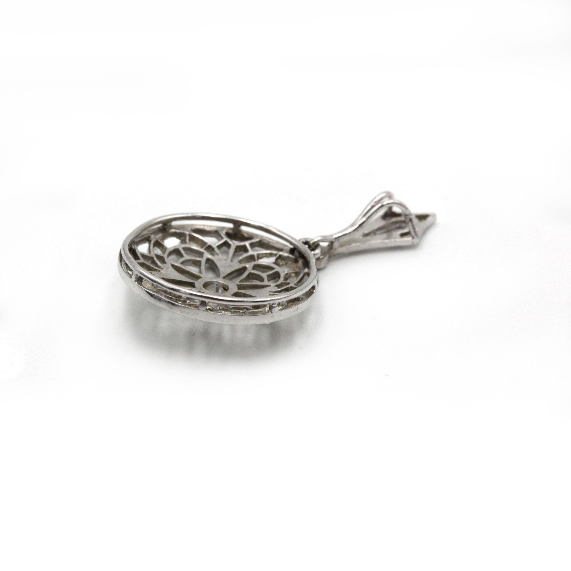 Questo raffinato ciondolo Art Déco è realizzato magistralmente in platino 950‰, famoso per la sua lucentezza argentea e la sua resistenza duratura. Il pezzo presenta un disco circolare traforato, meticolosamente traforato per formare un motivo