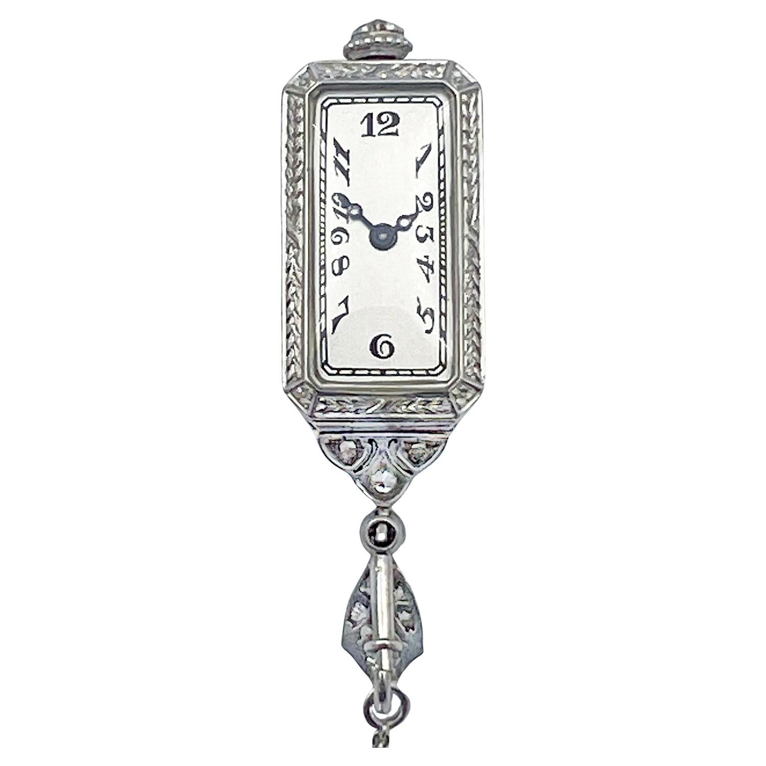 Platinum diamond pendant watch on long sautoir-style necklace chain.  The rectangular platinum case is finely crafted with pierced cut-out detailing and set with European and rose cut diamonds over a black enamel background.  The reverse side