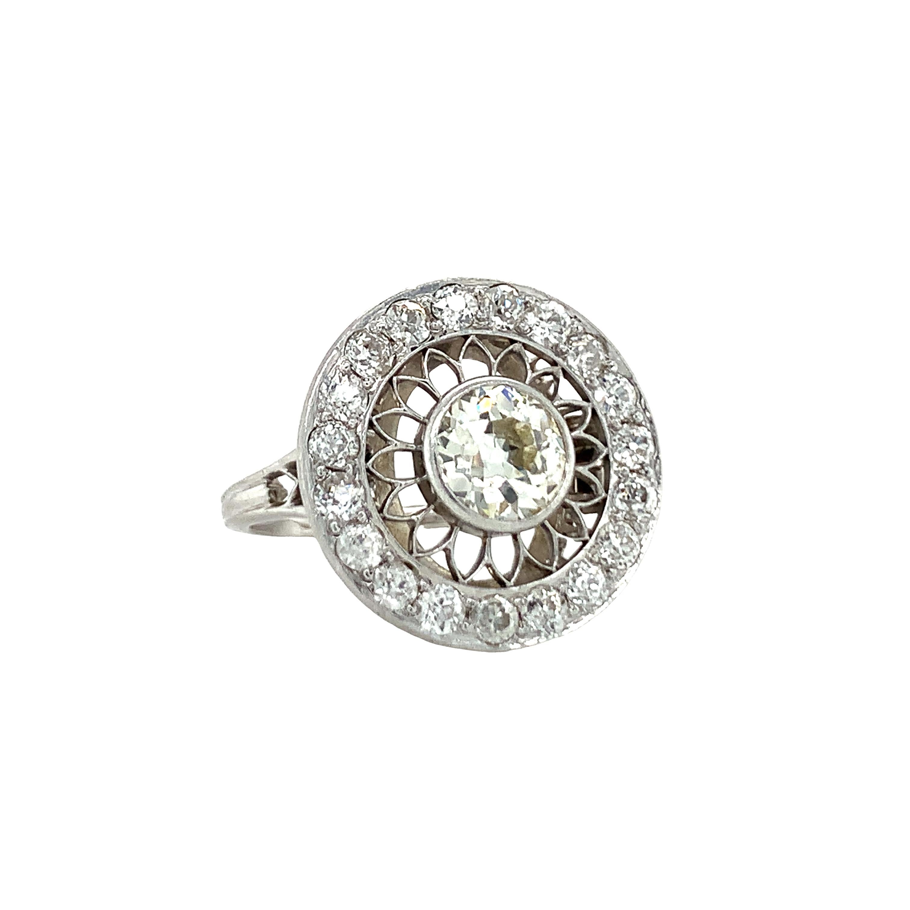 One Art Deco platinum diamond ring with circular open work design centering one bezel set, old European cut diamond weighing 1 ct. with K-L color and SI-1 clarity surrounded by 19 bead set, old European cut diamonds totaling 0.62 ct. with J color