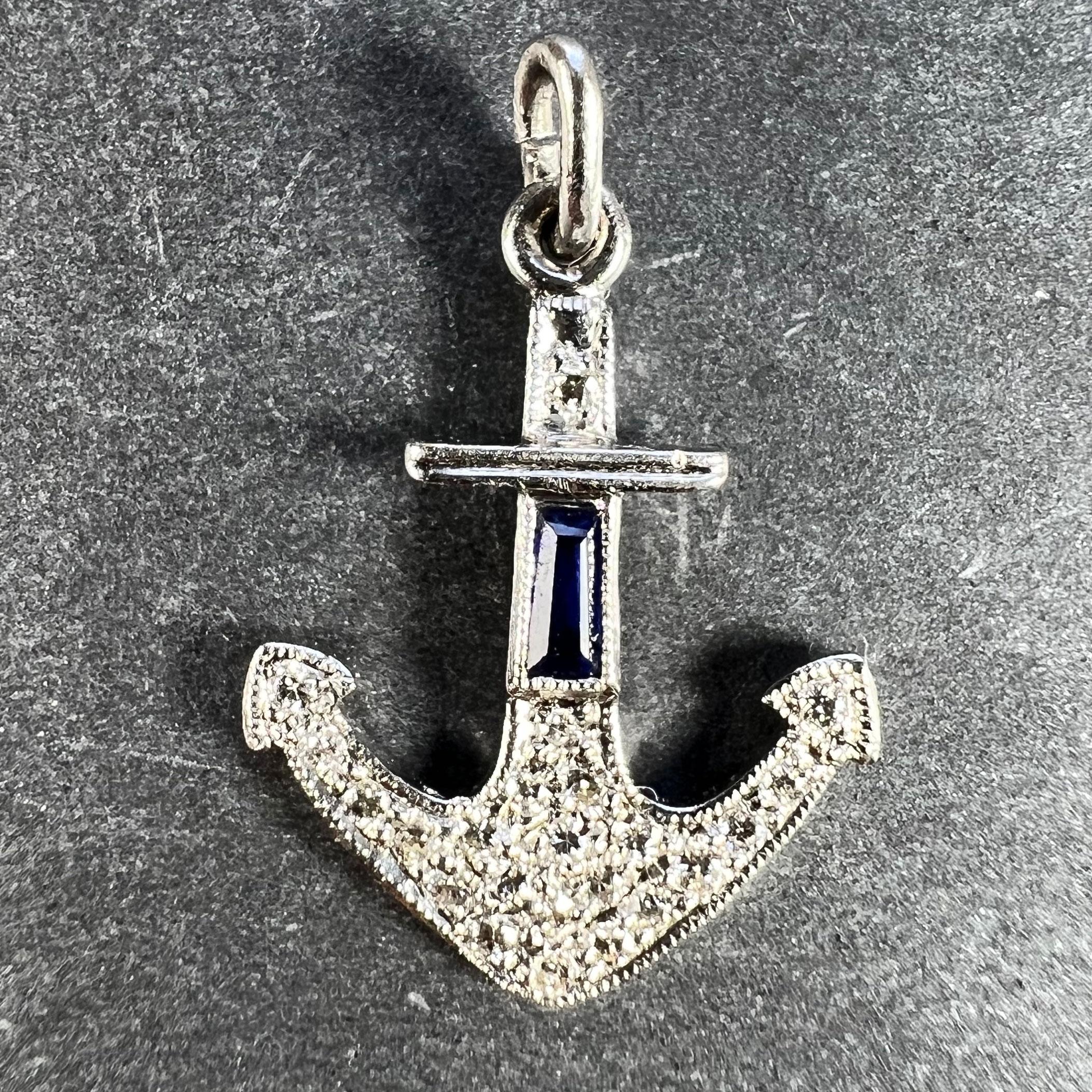 An Art Deco platinum charm pendant designed as an anchor, set with 23 round brilliant cut white diamonds with a total approximate weight of 0.30 carats and one tapered baguette cut blue sapphire with an estimated weight of 0.12 carats. Unmarked but