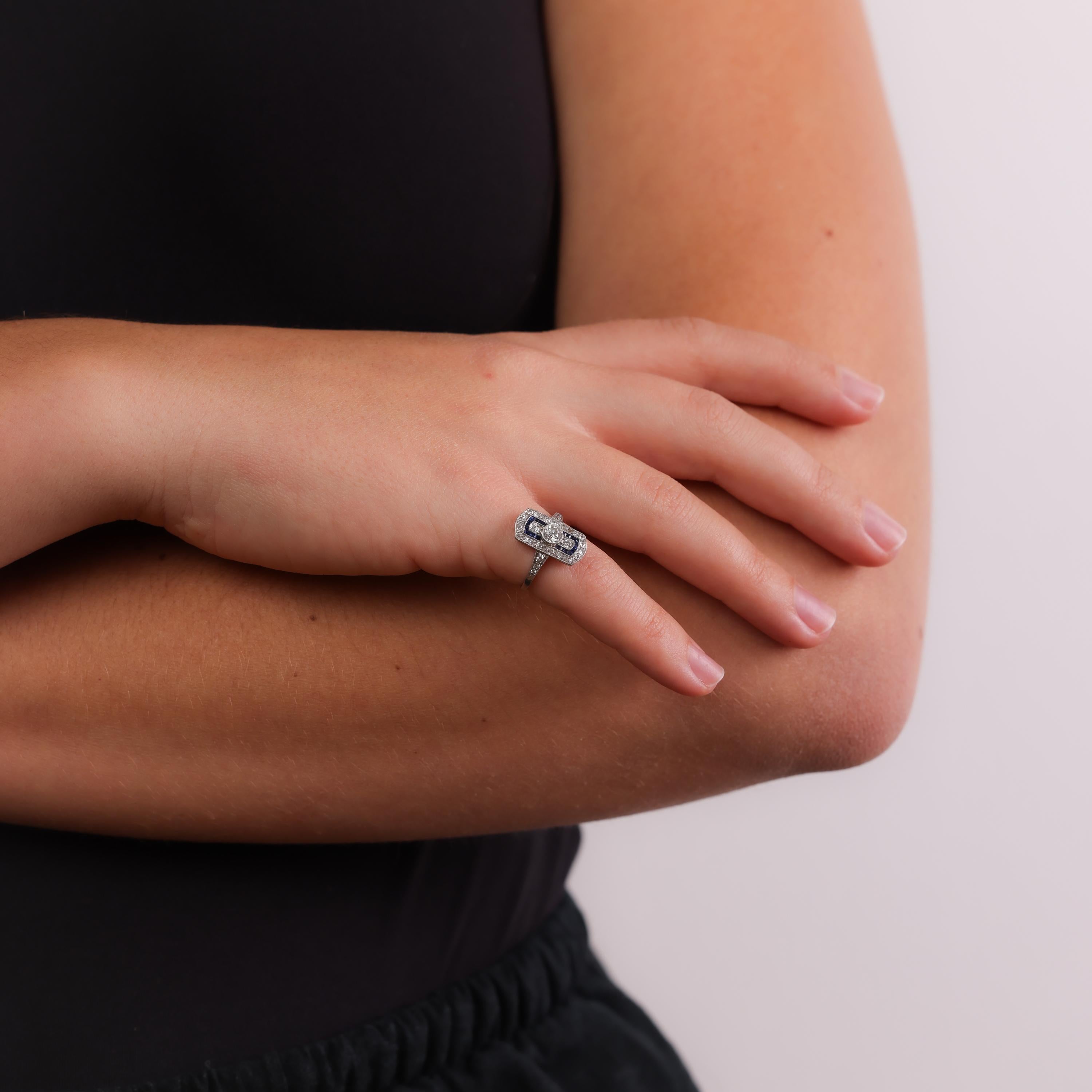 This exquisite Art Deco platinum ring highlights a brilliant old European cut diamond, framed by sparkling single-cut diamonds and vibrant French-cut sapphires. A refined and elegant design from the 1920s.

Center stone: Old European cut