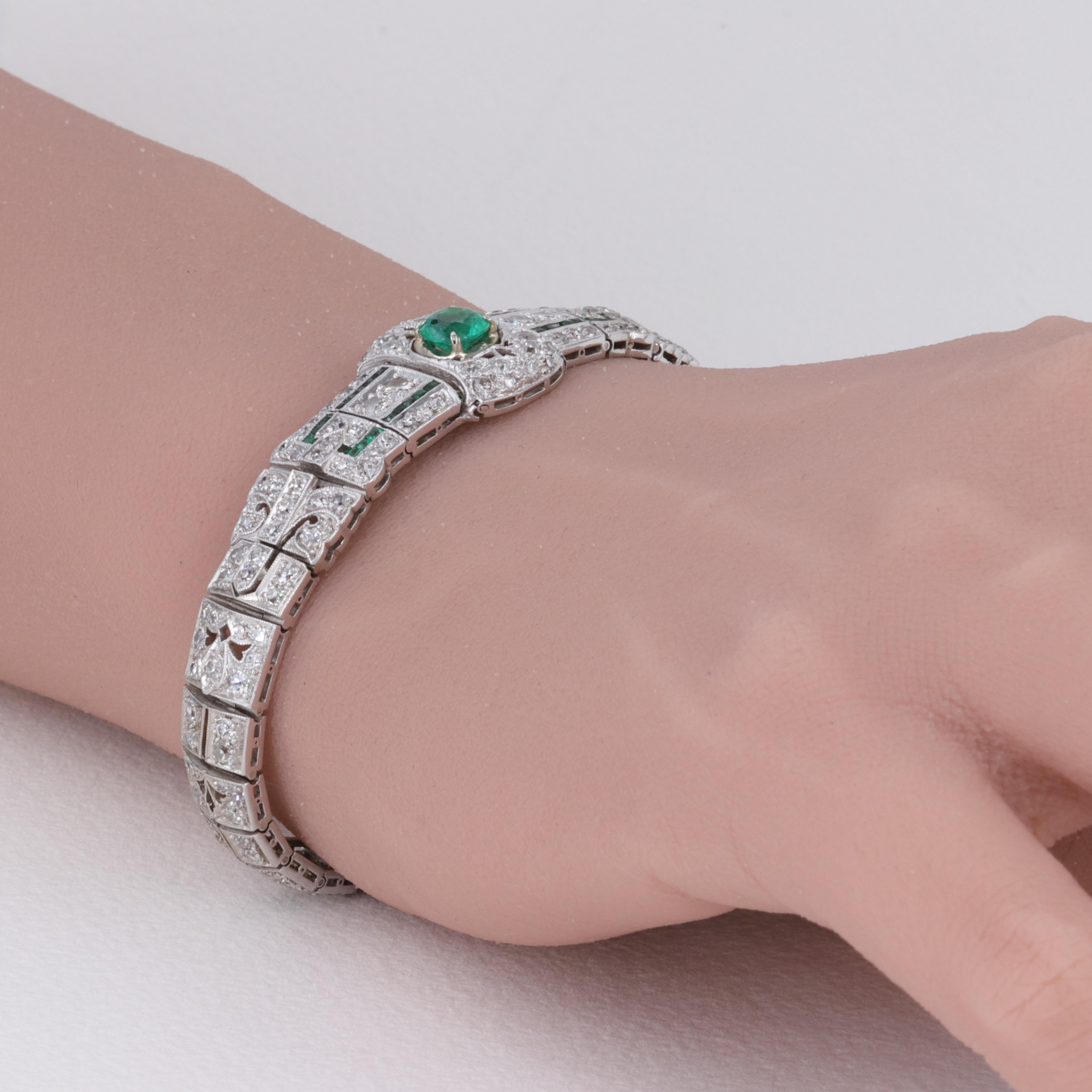 A gorgeous relic of the Art Deco era, this bracelet intricately crafted of platinum features an approximately .70 carat center round emerald with another approximately .20 carats total emerald baguettes and approximately 3.50 carat total weight of