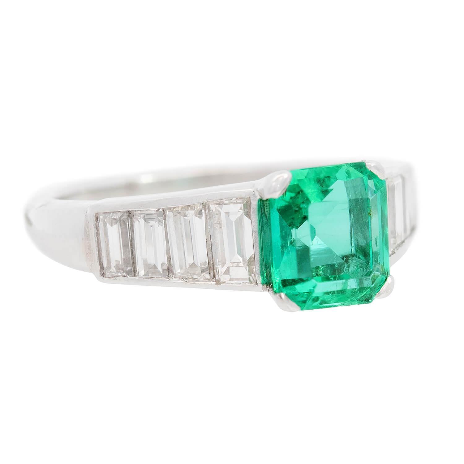 A gorgeous emerald and diamond ring from the Art Deco (ca1920) era! Crafted in platinum, this ring features a central square-cut Colombian emerald, which displays a wonderful rich, green hue. The stone is held within a four-prong setting, and has a