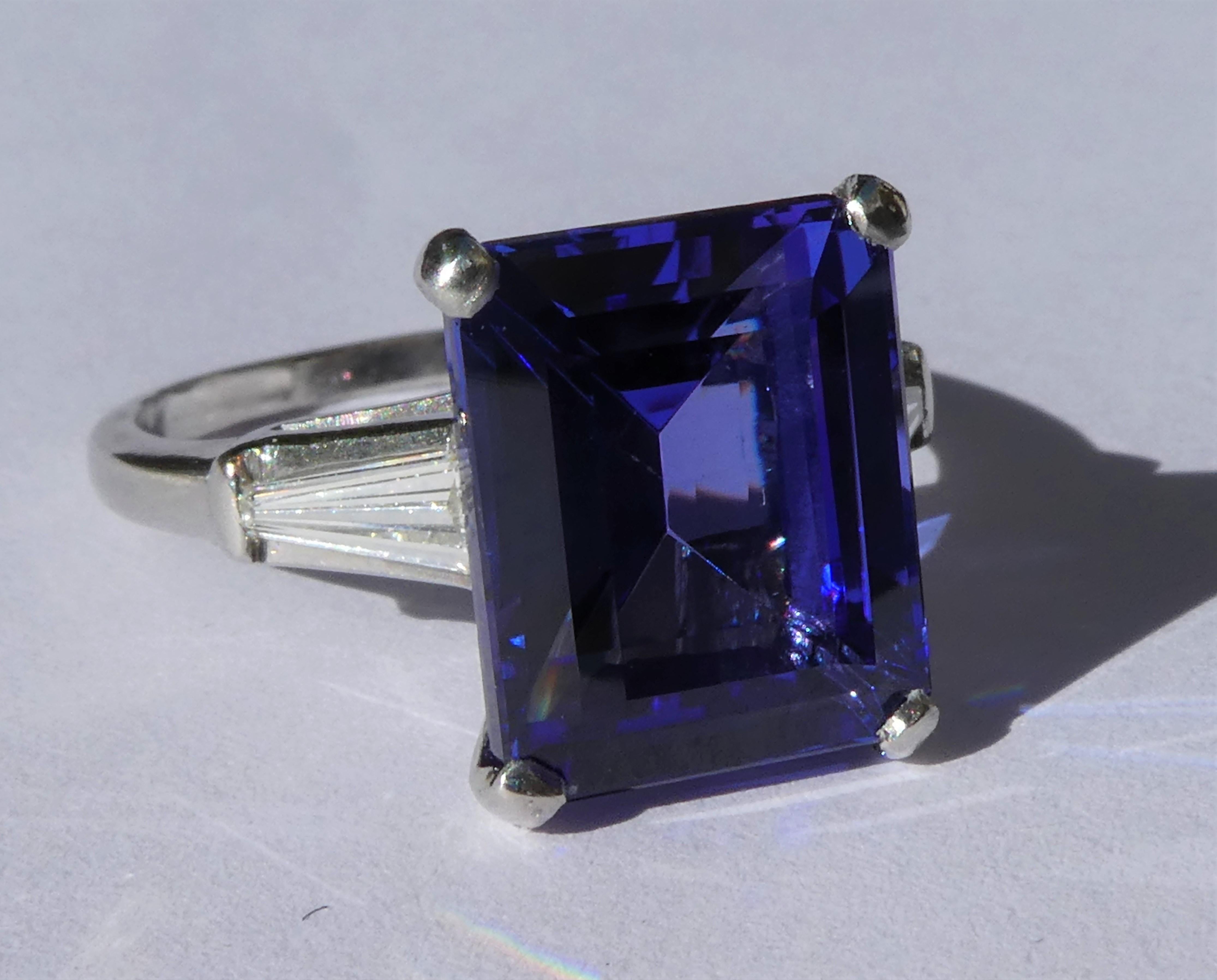 This beautiful ring was handmade in platinum in the 1920s in the United States. The natural rich violet blue tanzanite in emerald cut weighs 6.5 carat and was set in four claws in a later period. On the side there are two diamonds in trapeze cut of
