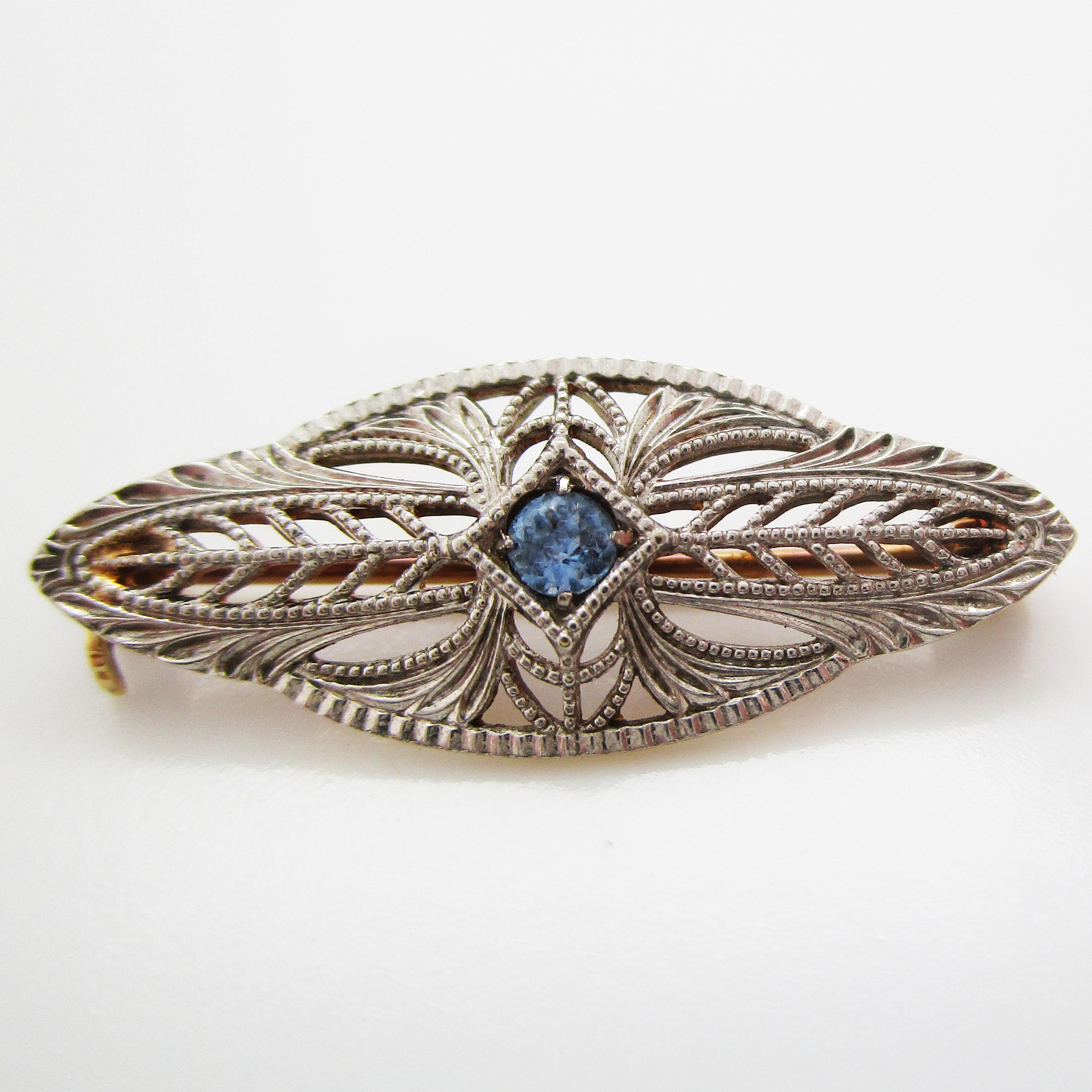 This gorgeous Deco pin is in platinum and has fine filigree details and a stunning Montana sapphire center. The platinum is the perfect contrast against the steely blue sapphire, and the filigree details create a lacey look that will go with