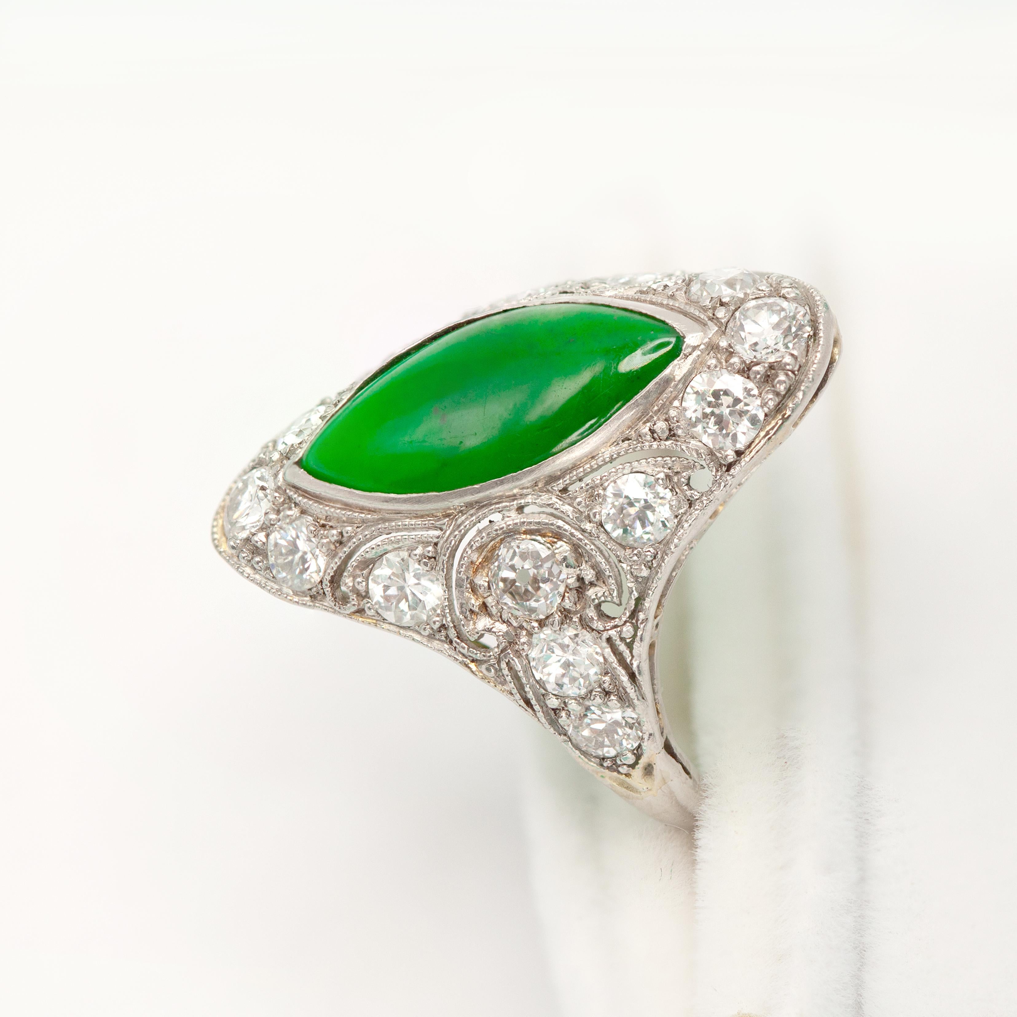 An exquisite Art Deco platinum Jade diamond ring showcases a vibrant marquise cut jadeite cabochon of rich, translucent emerald green, surrounded by 16 good quality old European and old mine cut diamonds, weighing approximately 1.00 carat, in G
