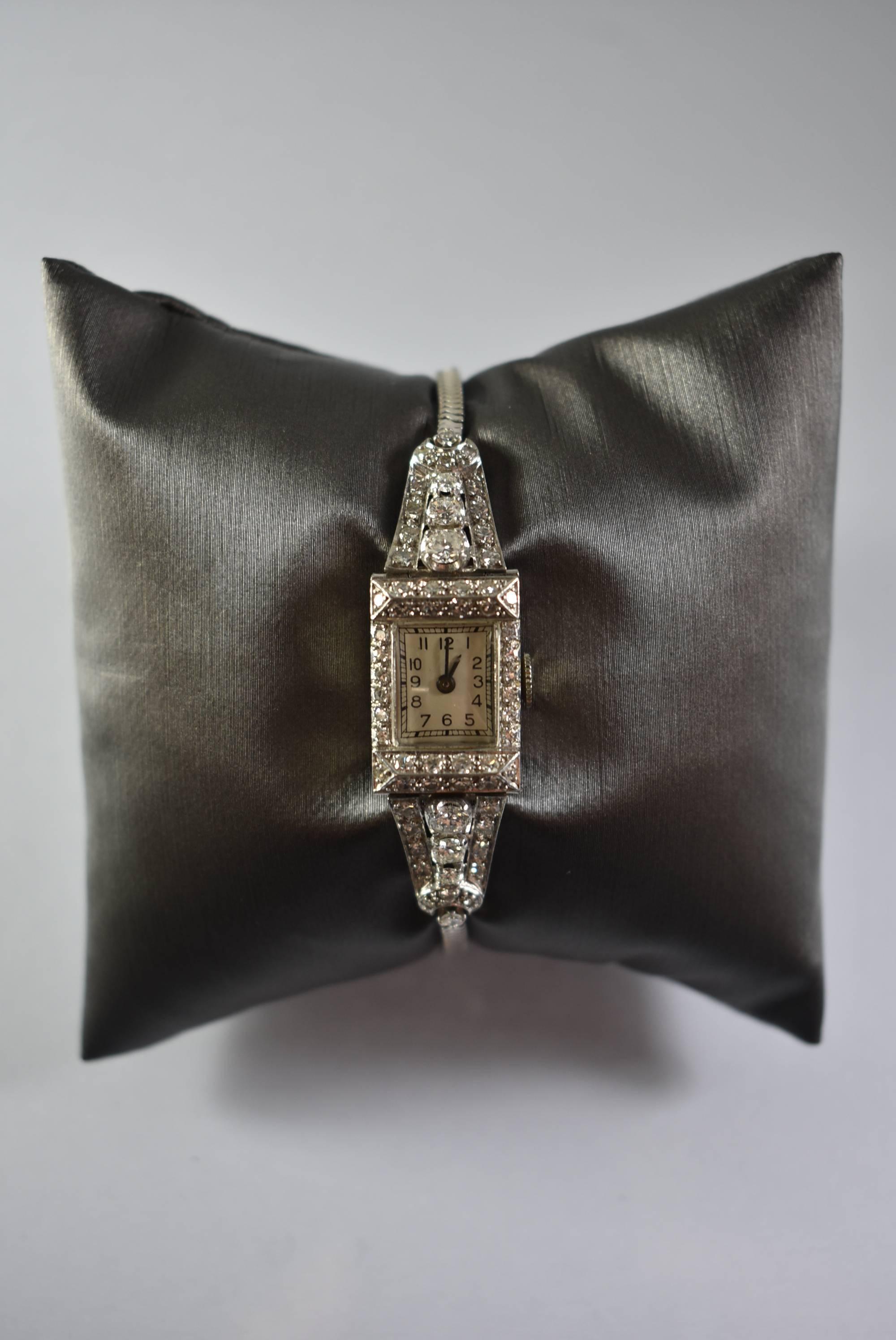 Eine atemberaubende Art Deco Stil Platin Damenarmbanduhr mit Diamanten. Diese wunderschöne Uhr besitzt ein Platingehäuse, das von 1,75 Karat Diamanten umgeben ist. Das Gehäuse ist mit 900 Platin gekennzeichnet. Sie hat ein Uhrwerk mit 17 Steinen,