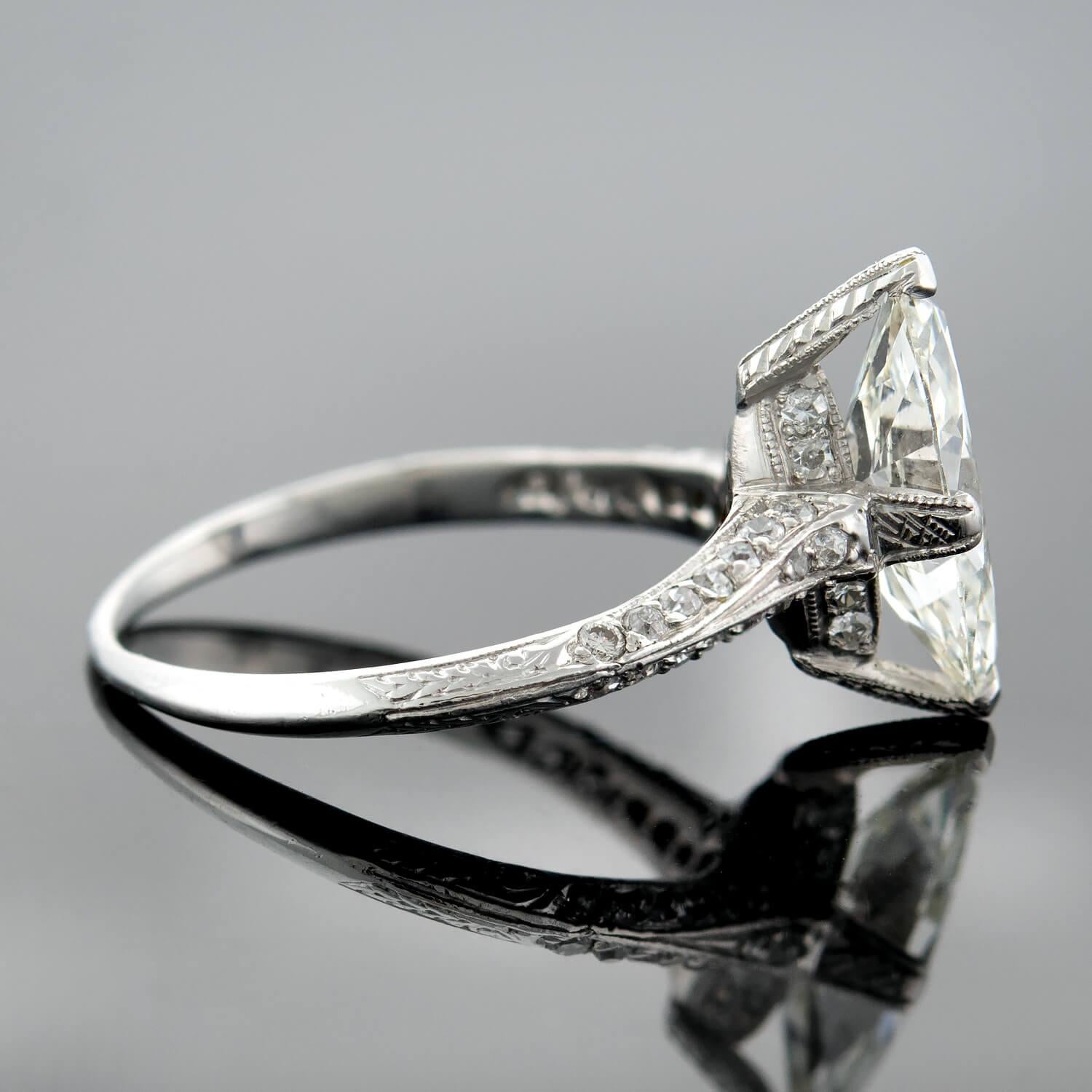 A gorgeous Art Deco diamond engagement ring from the 1920s era! Crafted in platinum, this lovely piece has a stunning Marquise Cut diamond that is prong set prominently at the center. The diamond, which rests in a beautifully etched 4 prong setting,