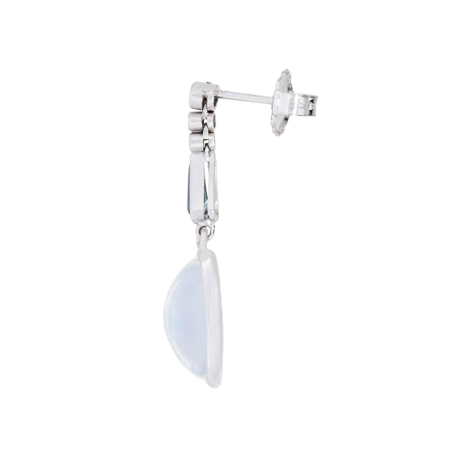 A stunning pair of moonstone, sapphire, and diamond earrings from the Art Deco (ca1920s) era! These stunning earrings are crafted in platinum and begin with three small diamonds held within milgrained bezel settings. The bottom of the diamond