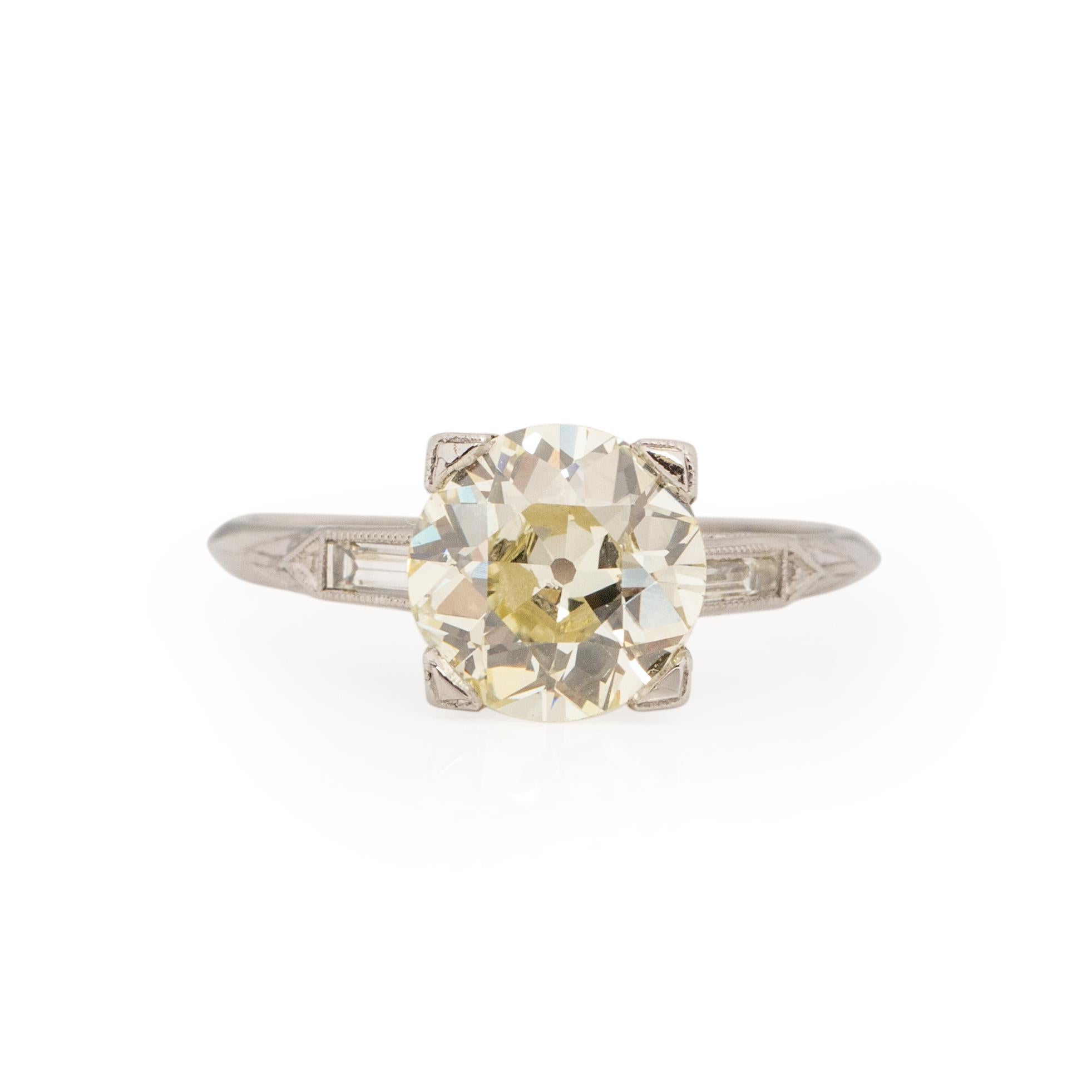 Here we have a bold and beautiful warm colored vintage solitaire engagement ring. This ring is crafted in platinum, the simple classic shank holds two perfectly cut baguette diamonds. Sitting on either side of a 2.52Ct old European cut warm colored