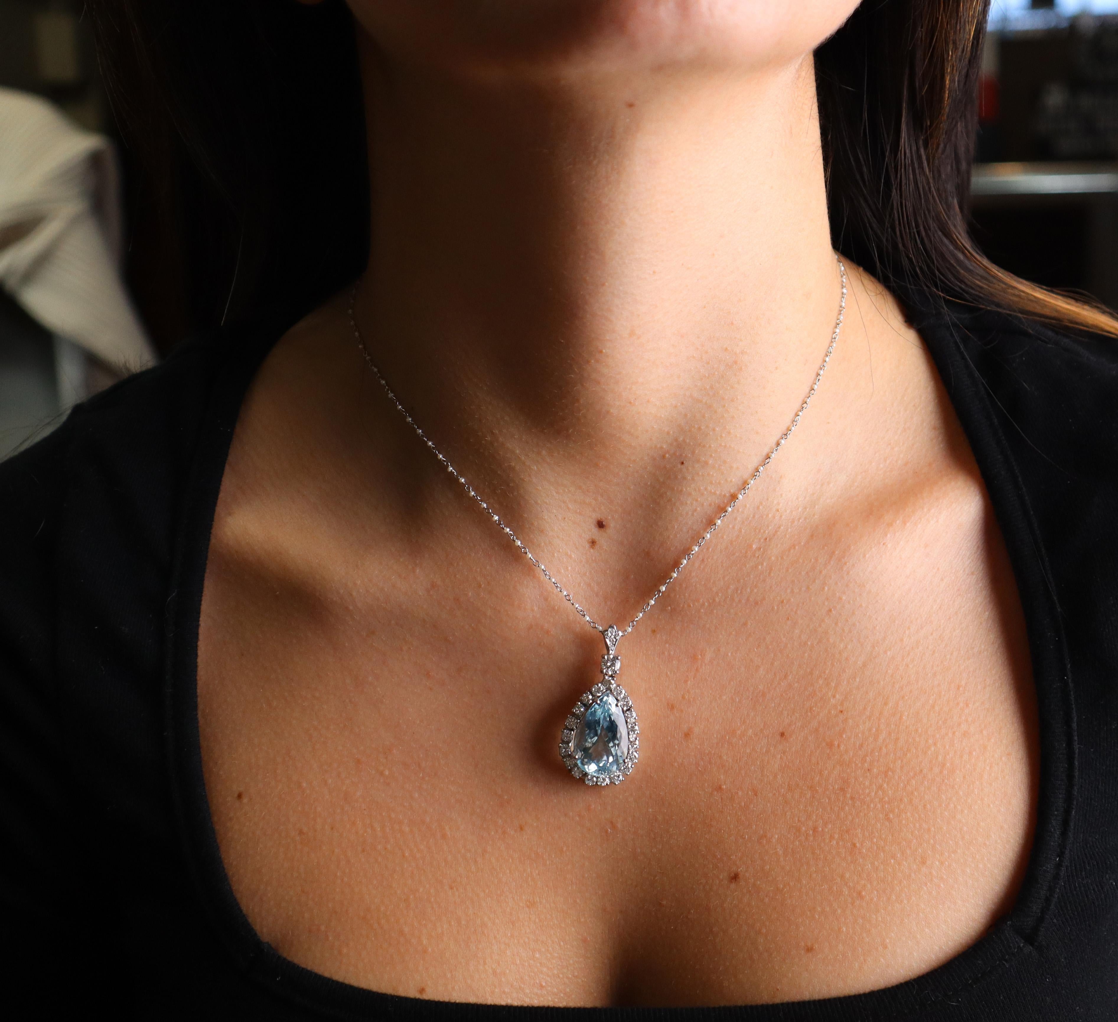 Questa splendida collana con ciondolo è realizzata in platino e presenta una splendida acquamarina a forma di pera del peso di circa 12,50 carati. L'acquamarina è circondata da diamanti di taglio rotondo per un totale di circa 1,20 carati, con un