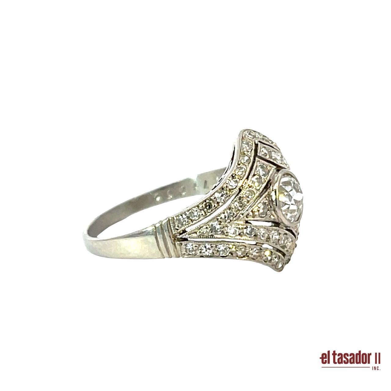 Questo squisito anello Art Deco in platino (4 grammi) presenta un diamante centrale con taglio a brillante di 0,51 carati, splendidamente incorniciato da un disegno geometrico traforato. La montatura è ulteriormente impreziosita da circa 0,50 carati