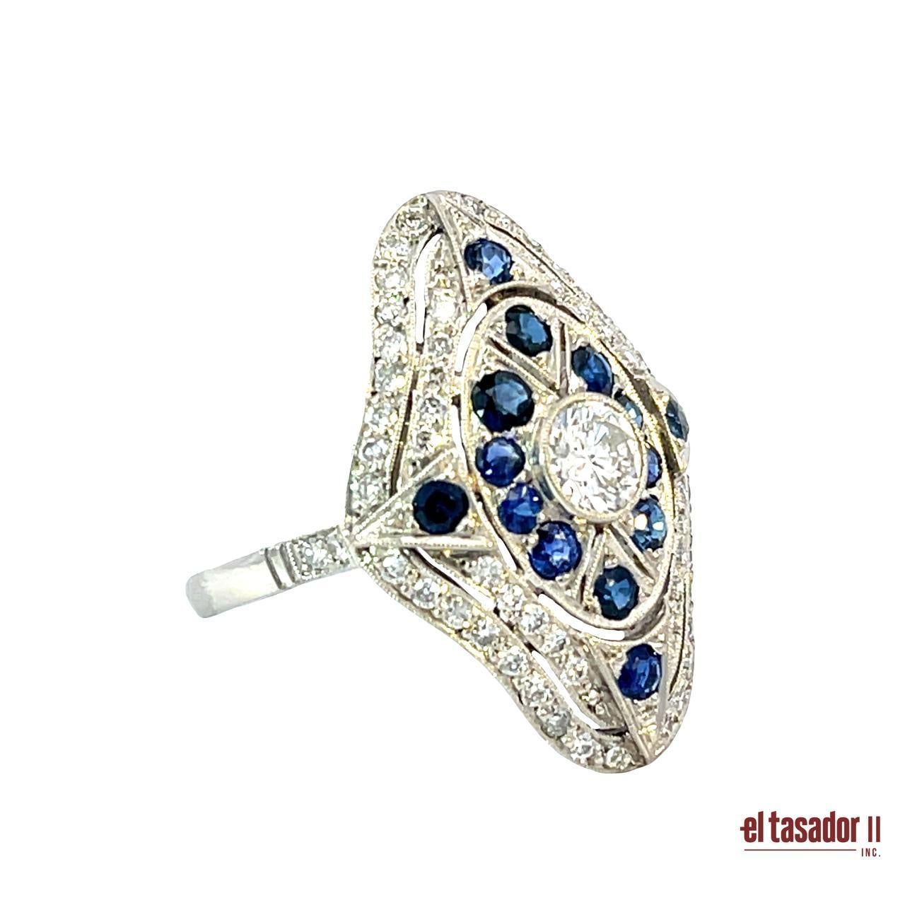 Cette élégante bague Art déco en platine, pesant 6,3 grammes, est ornée d'un brillant diamant central rond de 0,43 carat, entouré de 0,47 carat d'autres diamants étincelants. Accentué par 0,91 carats de saphirs bleus vifs, le design géométrique