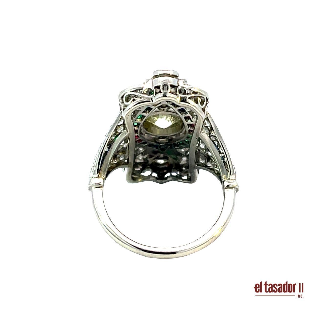 Questo sorprendente anello in platino di ispirazione Art Déco pesa 9,9 grammi e presenta un'audace composizione di linee geometriche e colori vivaci. Al centro, un diamante da 1,00 carati con taglio brillante è accentuato da altri 1,05 carati di