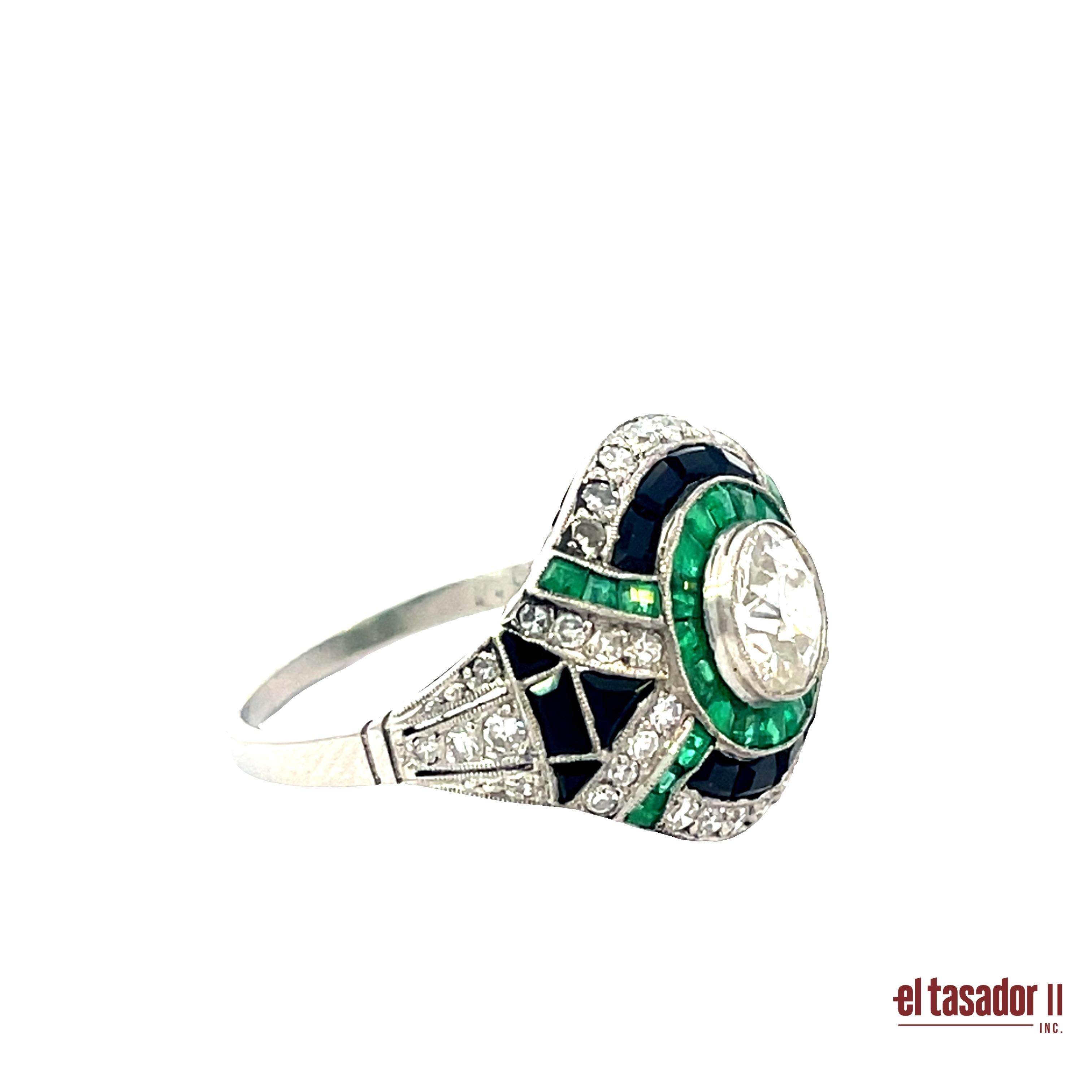 Este audaz y elegante anillo de platino presenta un diamante talla brillante de 0,89 quilates en su centro, enmarcado por 1,84 quilates de vívidas esmeraldas talla calibré. Acentuado con 0,45 quilates de diamantes talla brillante, el diseño se
