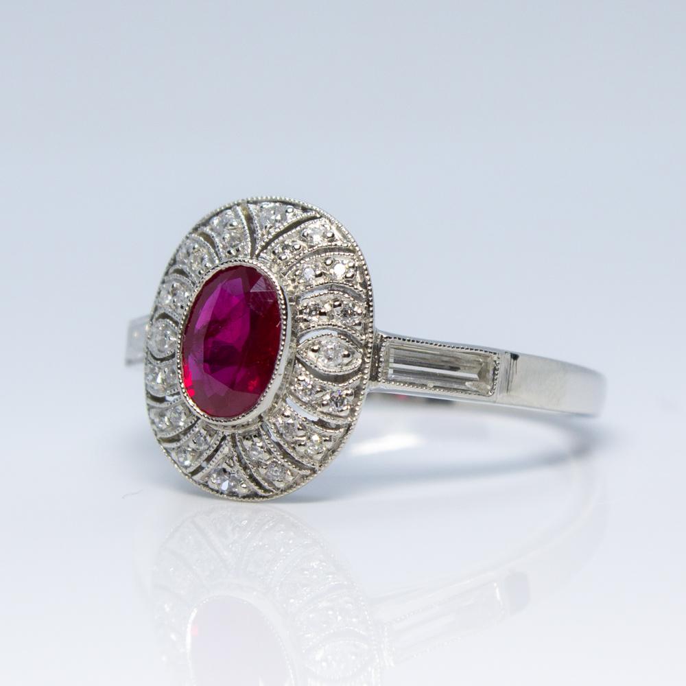 Composition: Platinum
Stones:
•	1 natural Burma ruby that weighs 0.70ctw.
•	2 baguette cut diamonds of H-VS2 quality that weigh 0.30ctw. 
•	28 Old mine cut diamonds of H-VS2 quality that weigh 0.25ctw.
Ring size: 7 ¾     
Ring face measurement: 