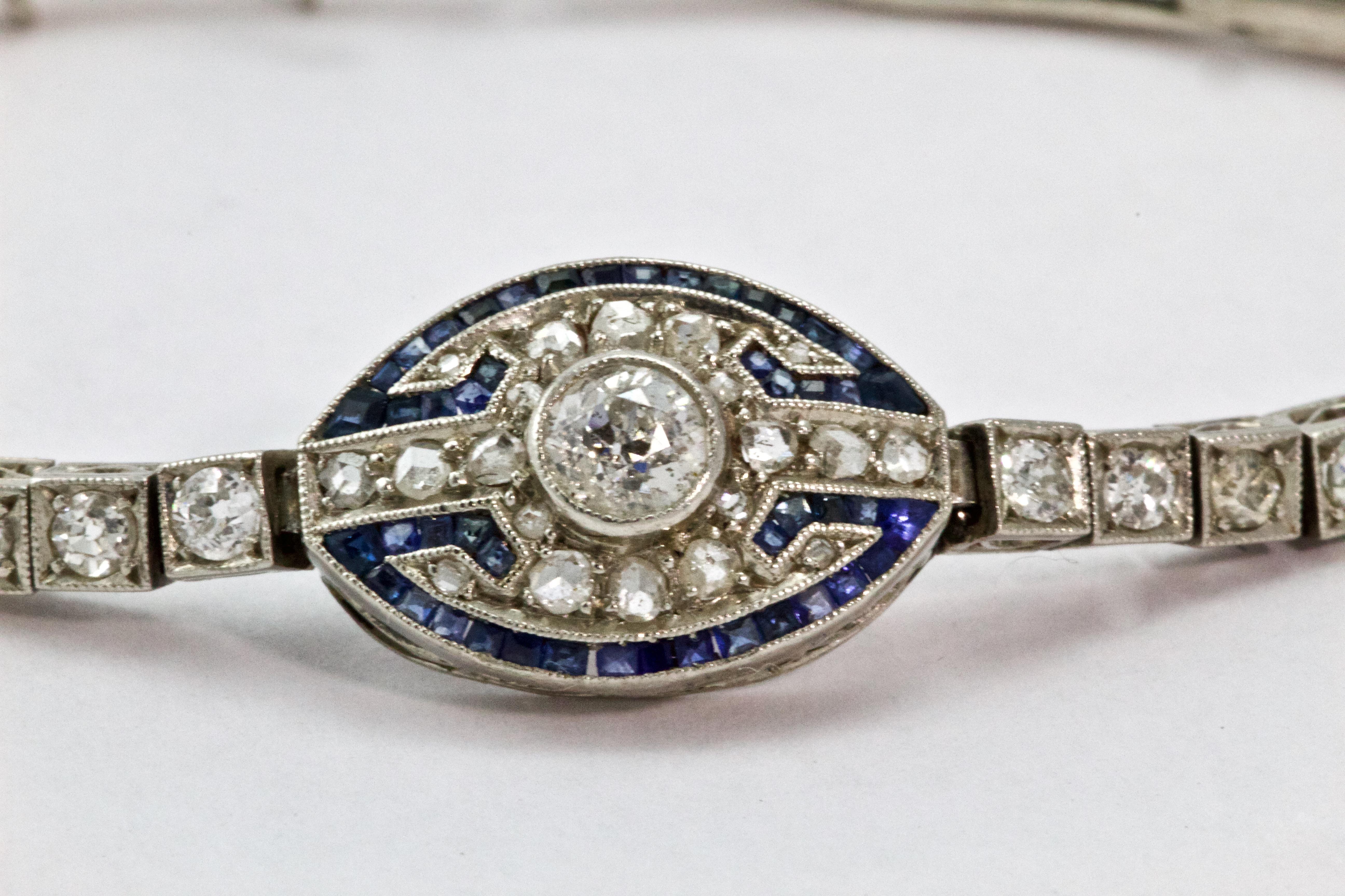 This gorgeous Art Deco bracelet features a central 25 point old European cut diamond placed in a pave set, rose cut diamond oval; with a calibre cut sapphire border and fine millegrain detailing. Either side of the central panel four further 5 point