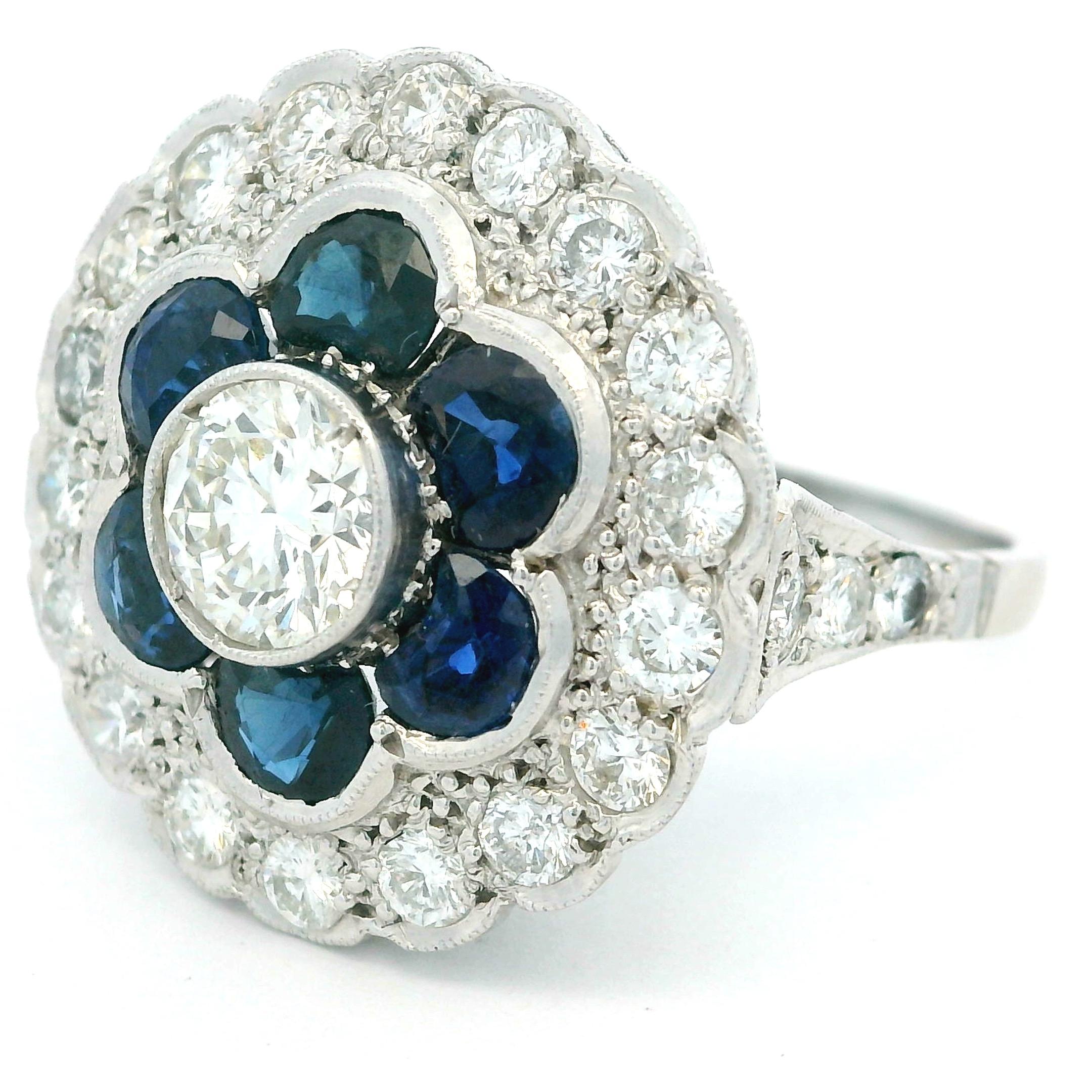 Ein prächtiger Art-Déco-Ring mit Saphiren und Diamanten, fein ausgearbeitet in Platin, um 1925-1935. In der Mitte befindet sich ein Brillant von ca. 0,50 Karat, umgeben von sechs blauen Saphiren von ca. 0,80 Karat Gesamtgewicht. Ein Halo aus zwanzig