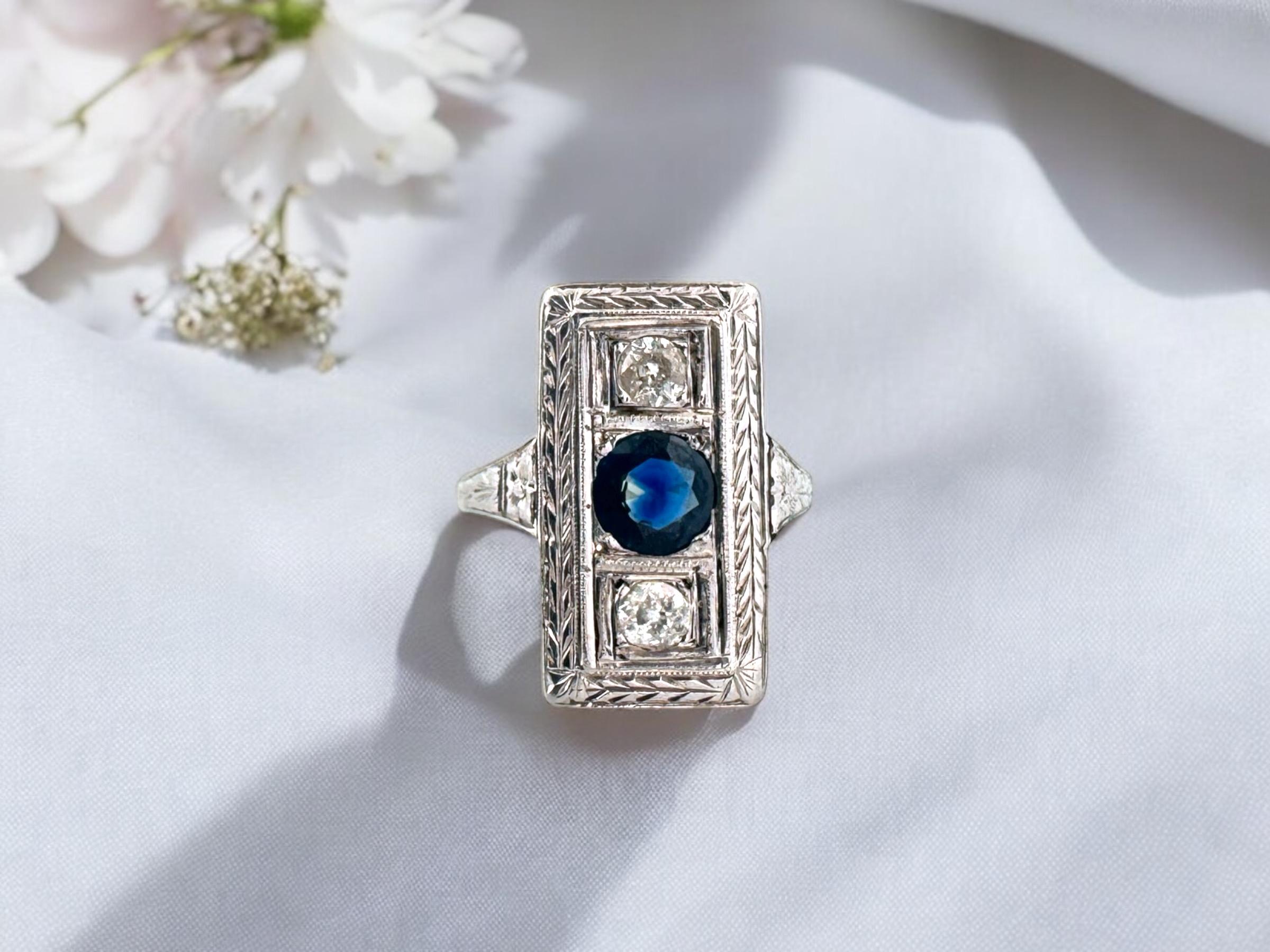 We are stunned by the simple beauty of this vintage ring!
The center natural sapphire is accented by lovely old mine cut diamonds.

Ring Details
Material: Platinum
Era: Art Deco 1920 - 1940
Ring Length: 3/4 Inch
Ring Width: 5/16 Inch 
Weight: 5.8