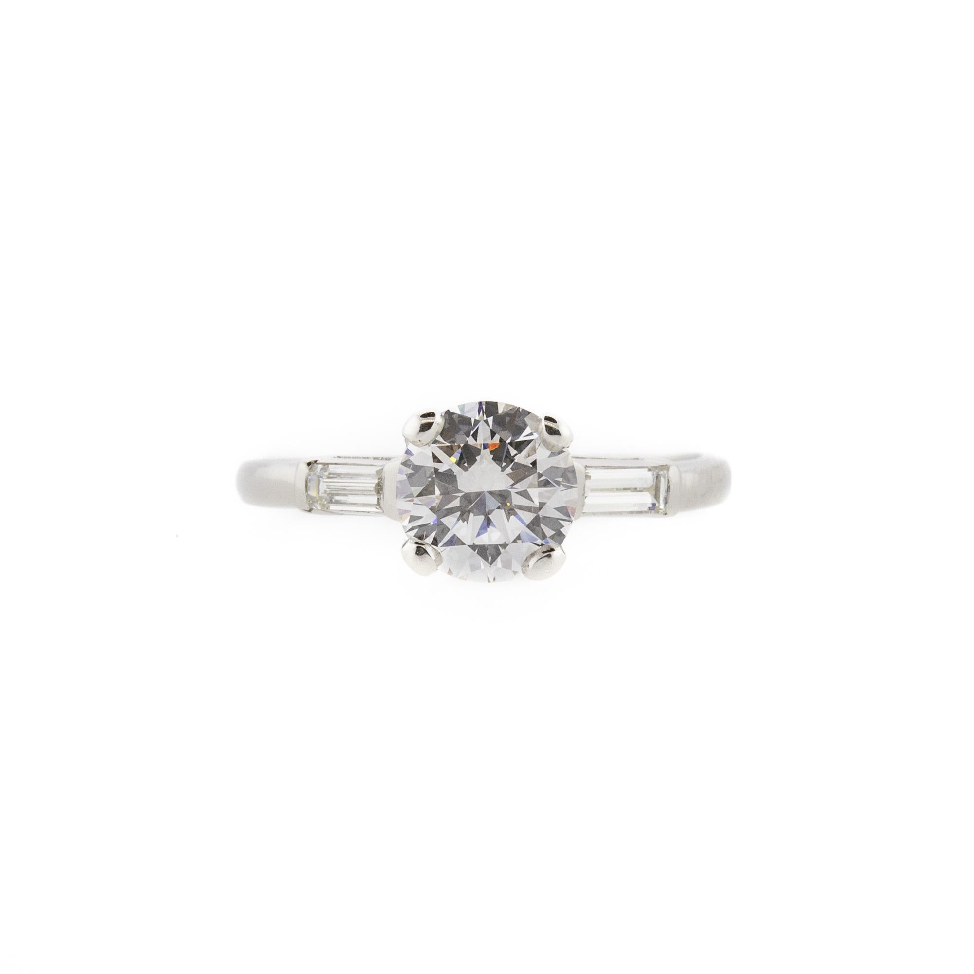 An original Art Deco setting featuring a breathtaking modern round brilliant cut center stone flanked by two equally gorgeous baguette diamonds. The center diamond is 1.14ct and rated at F in color and VVS2 in clarity set in lustrous platinum. This