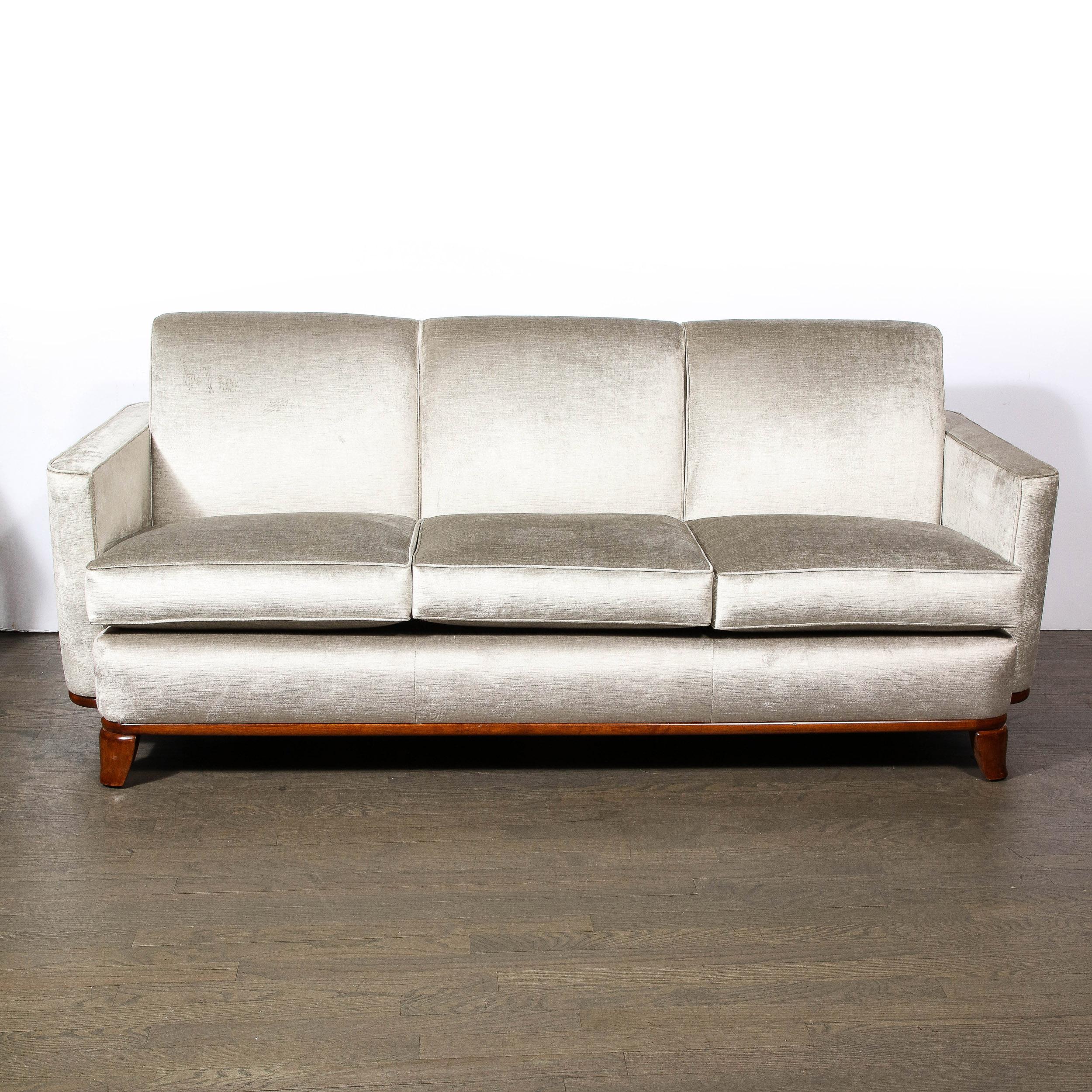 This stunning Art Deco Machine Age sofa was realized by the legendary Eugene Schoen in the United States circa 1935. It features three seat and back cushions; streamlined sides; and a stacked skyscraper style back- all newly reupholstered in a