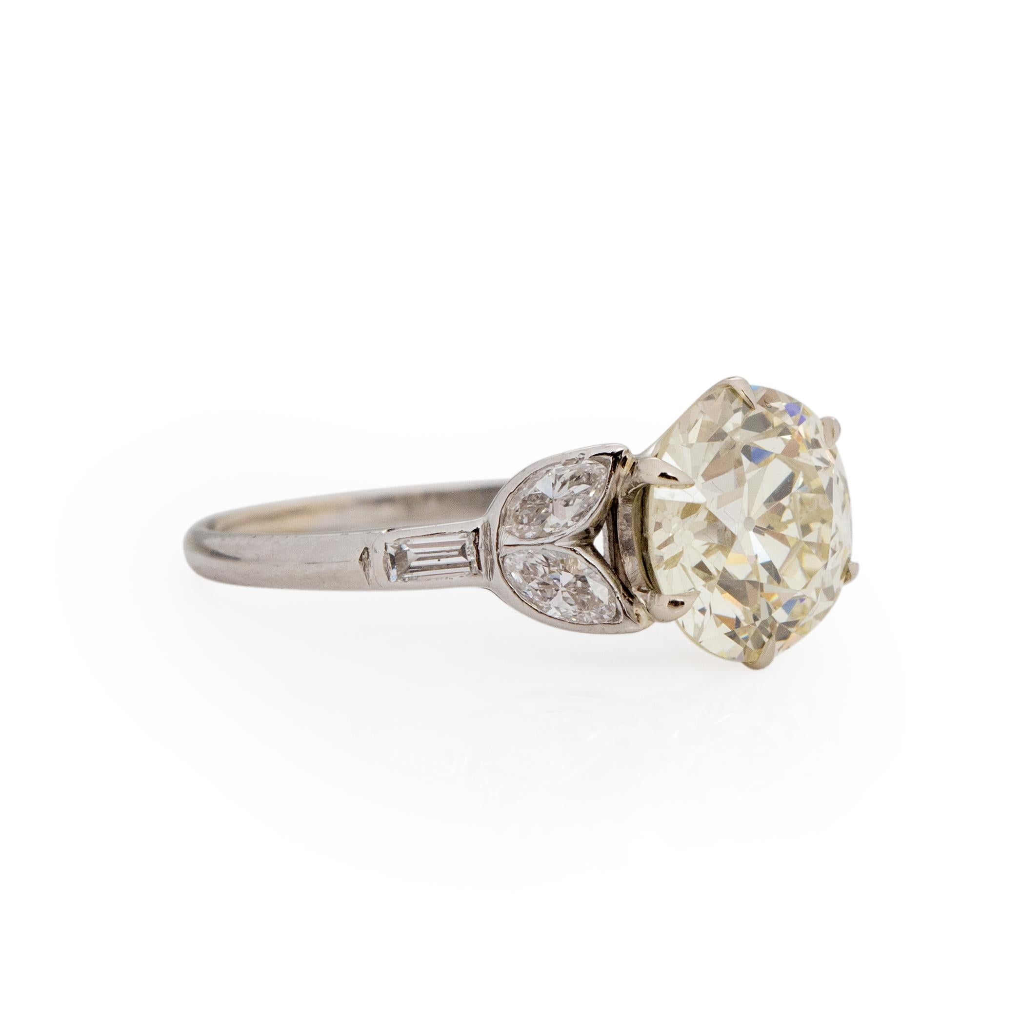 Here we have a beautiful flower motif art deco solitaire engagement ring. The outstanding 3 Ct old European cut diamond it held by a delicate leaf design that has four perfectly cut Marquee shape diamonds giving a split shank feel. Lengthening the
