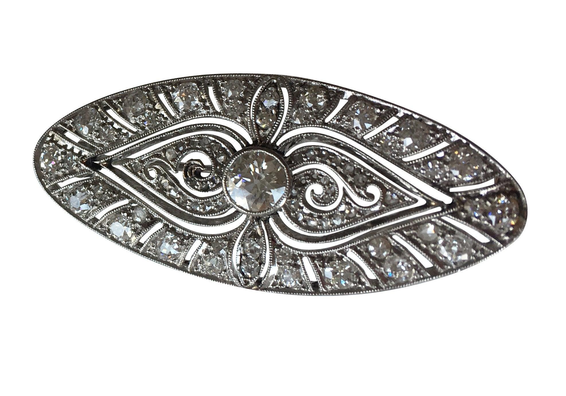An early 20th century oval diamond set panel with open pierced work finish. At the centre of the panel a brilliant cut diamond in a rub over setting. The diamond weighs .53ct Assessed F colour VS1. The brooch is grain set throughout with a further