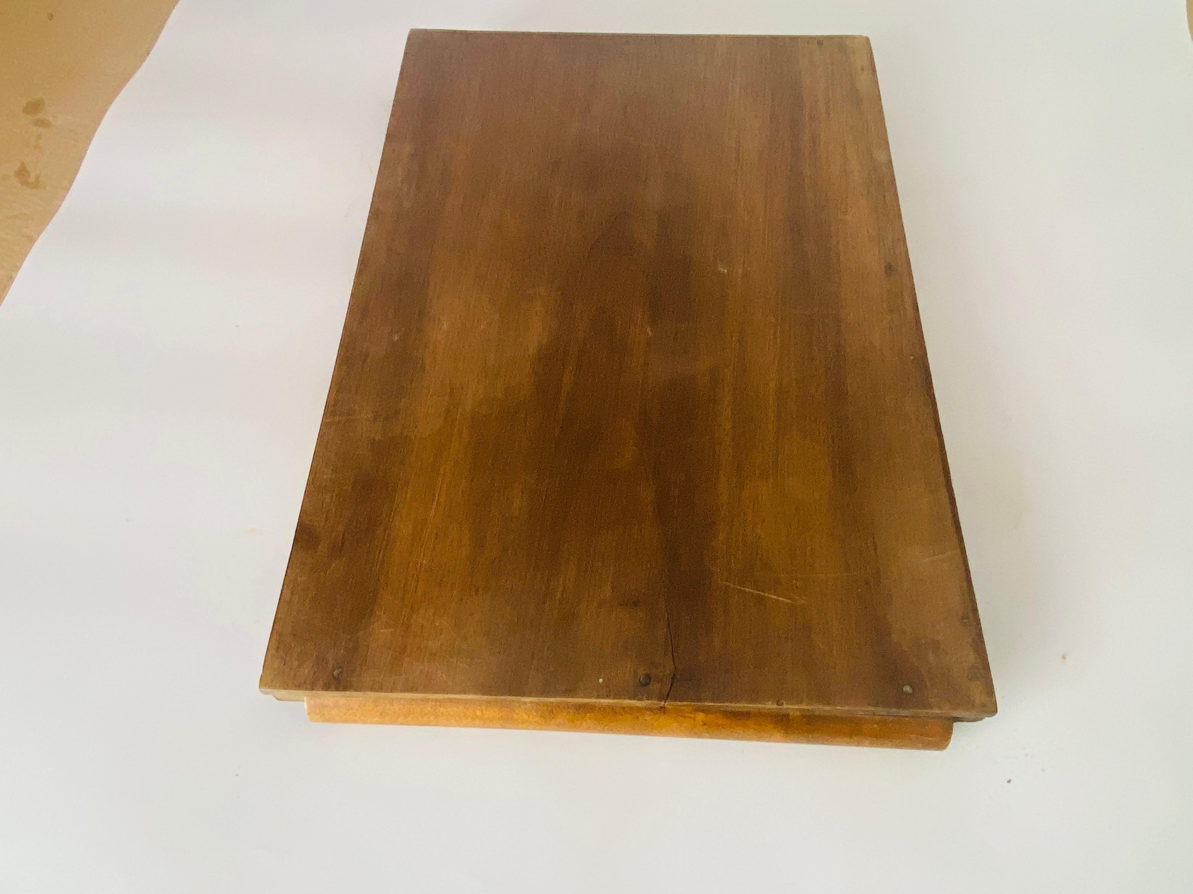 Dieses Tablett ist ein Tablett aus der Zeit des Art-Deco. Es ist aus Holz, ,  Sie hat eine rechteckige Form und endet mit zwei Holzgriffen. Seine Farbe ist braun, es wurde in den 1940er Jahren in Frankreich hergestellt.