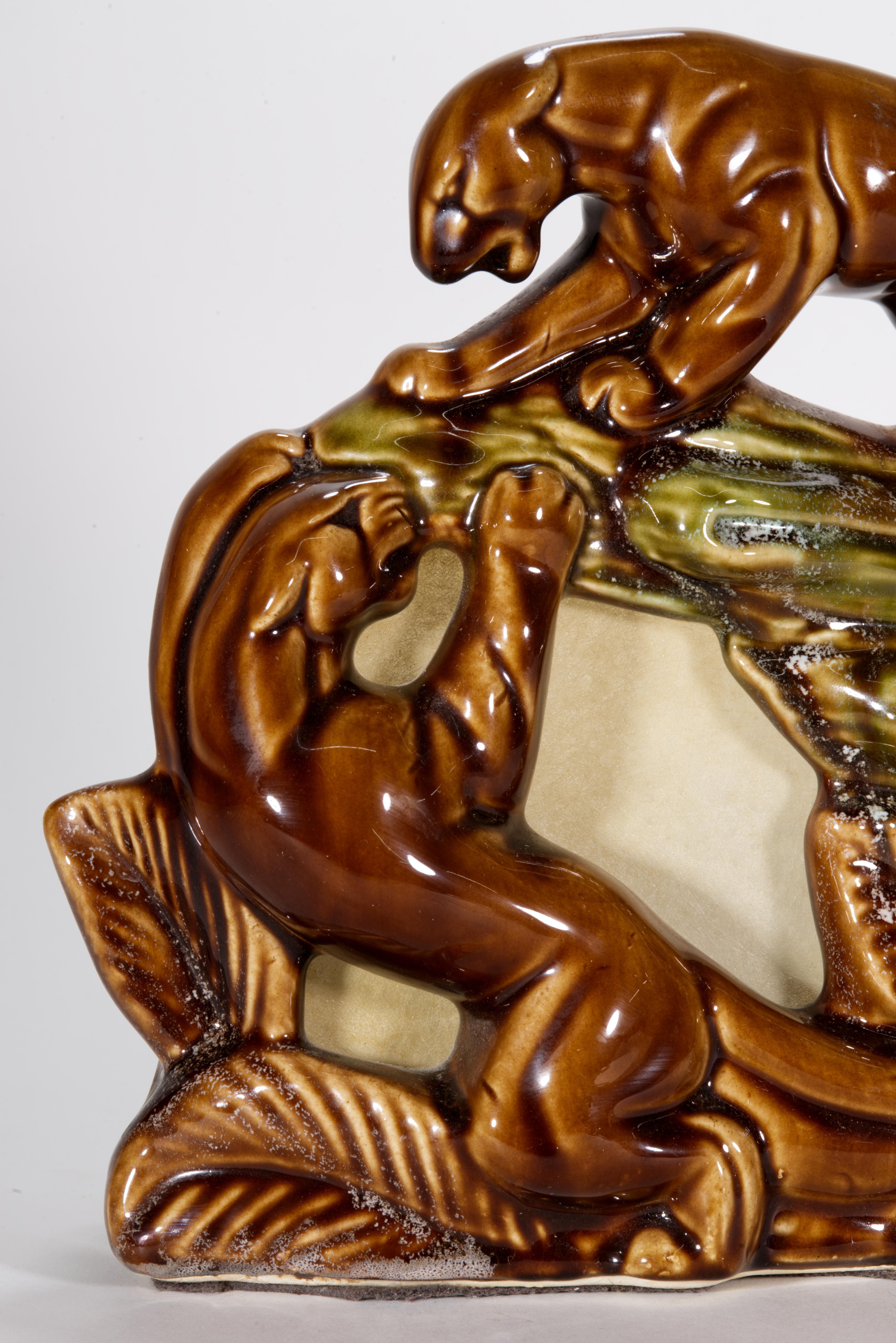  Rare vintage ceramic TV lamp features two playing panthers or wild cats in exotic forest or jungle background, sculpted in Art Deco style. One cat is holding high ground on a rock or large wood trunk, and another is reaching up from the ground. The