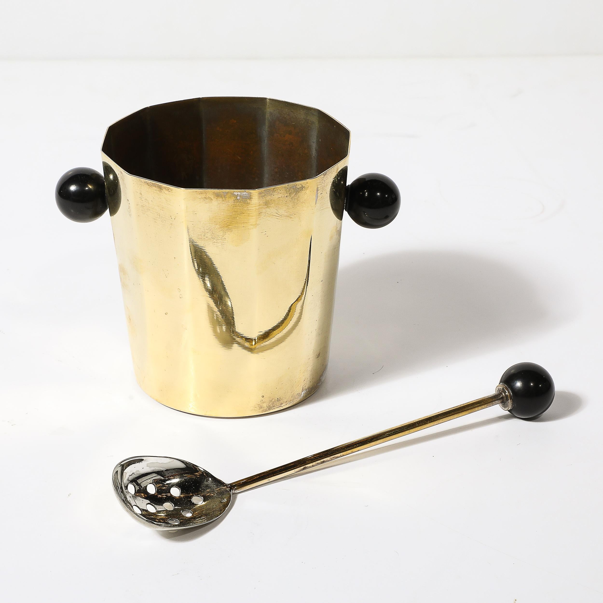 This beautifully achieved Art Deco Polished Brass & Bakelite Ice Bucket W/ Matching Scoop originates from France, Circa 1930. Features a faceted form with handles of black bakelite spheres on either side which matches the pommel of the ice scoop. A