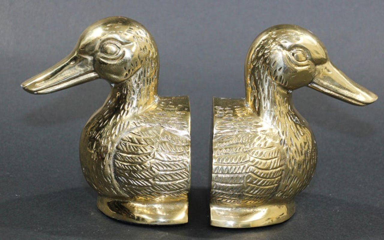 Pair of polished cast metal brass Art Deco decorative duck bookends.
Set of unique rare heavy polished gold brass large Mallard duck sculpture bust bookends.
Vintage pair of polished cast brass Mallard duck bust bookends, circa 1950. 
Pair of gold