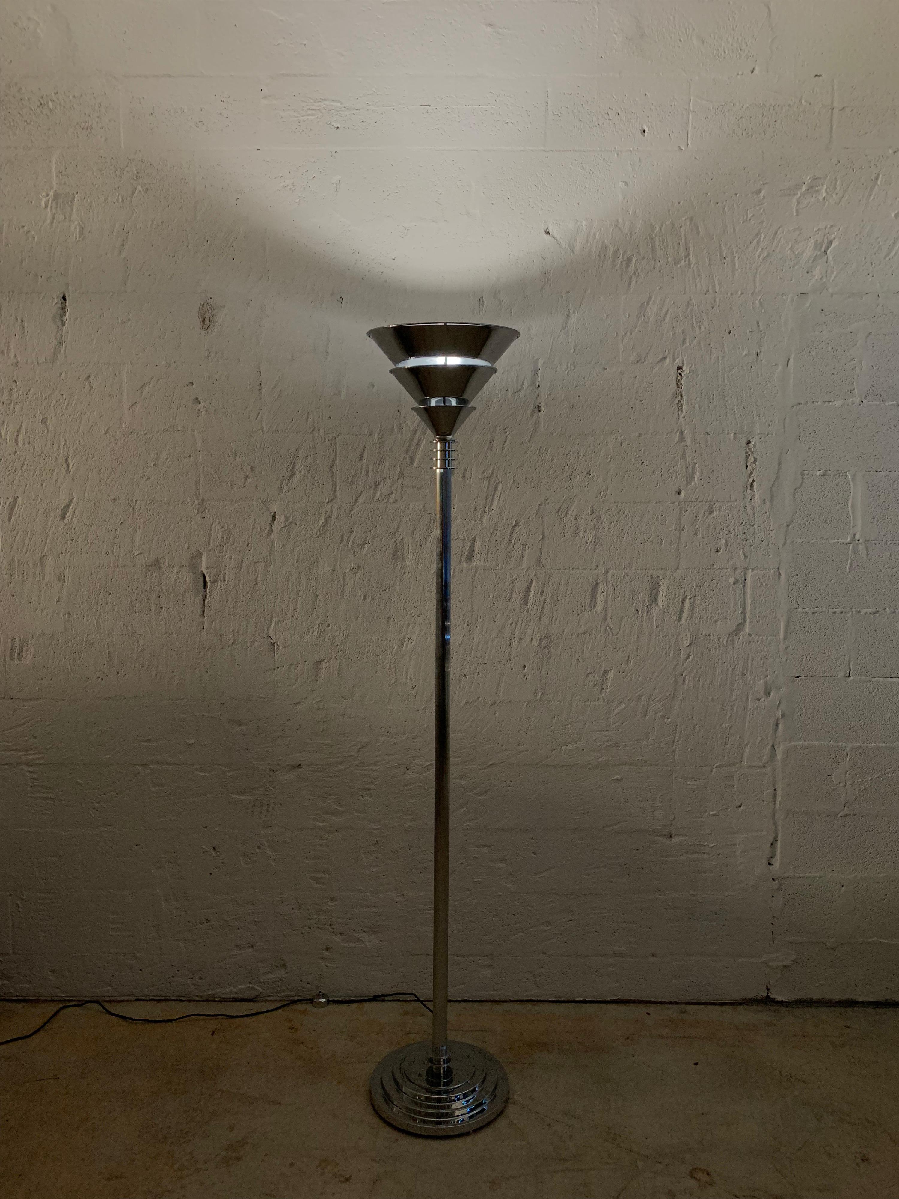 Art Deco torchiere or floor lamp, with a stacked base, reeded shaft body, and triple fluted stacked up light. Rendered in heavy polished chrome-plated steel with twisted silk cord and chrome foot switch, Jean Perzel style.