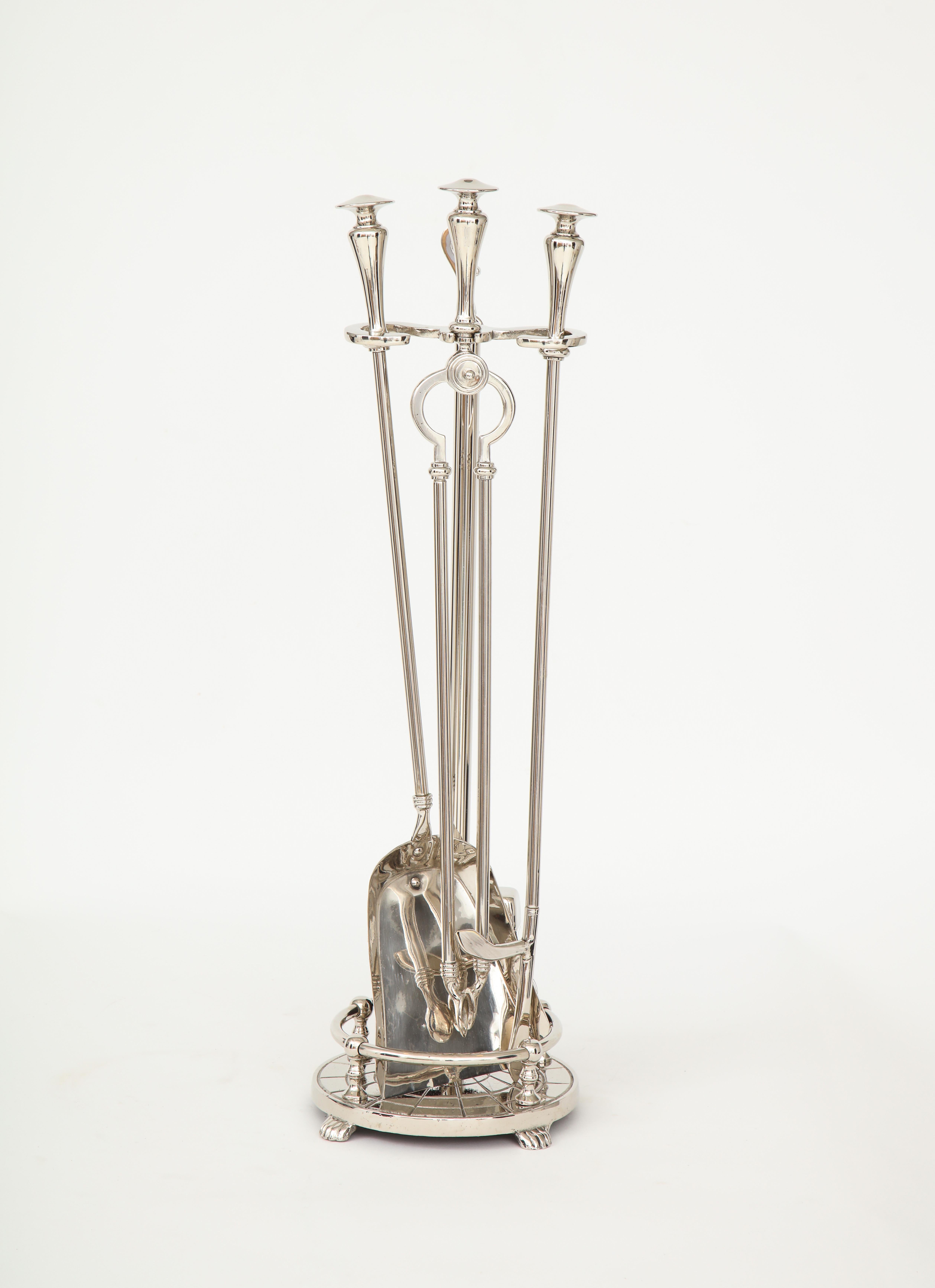 Set of Art Deco polished nickel fire tools featuring stylized finials. Set includes stand, poker, broom, and shovel.