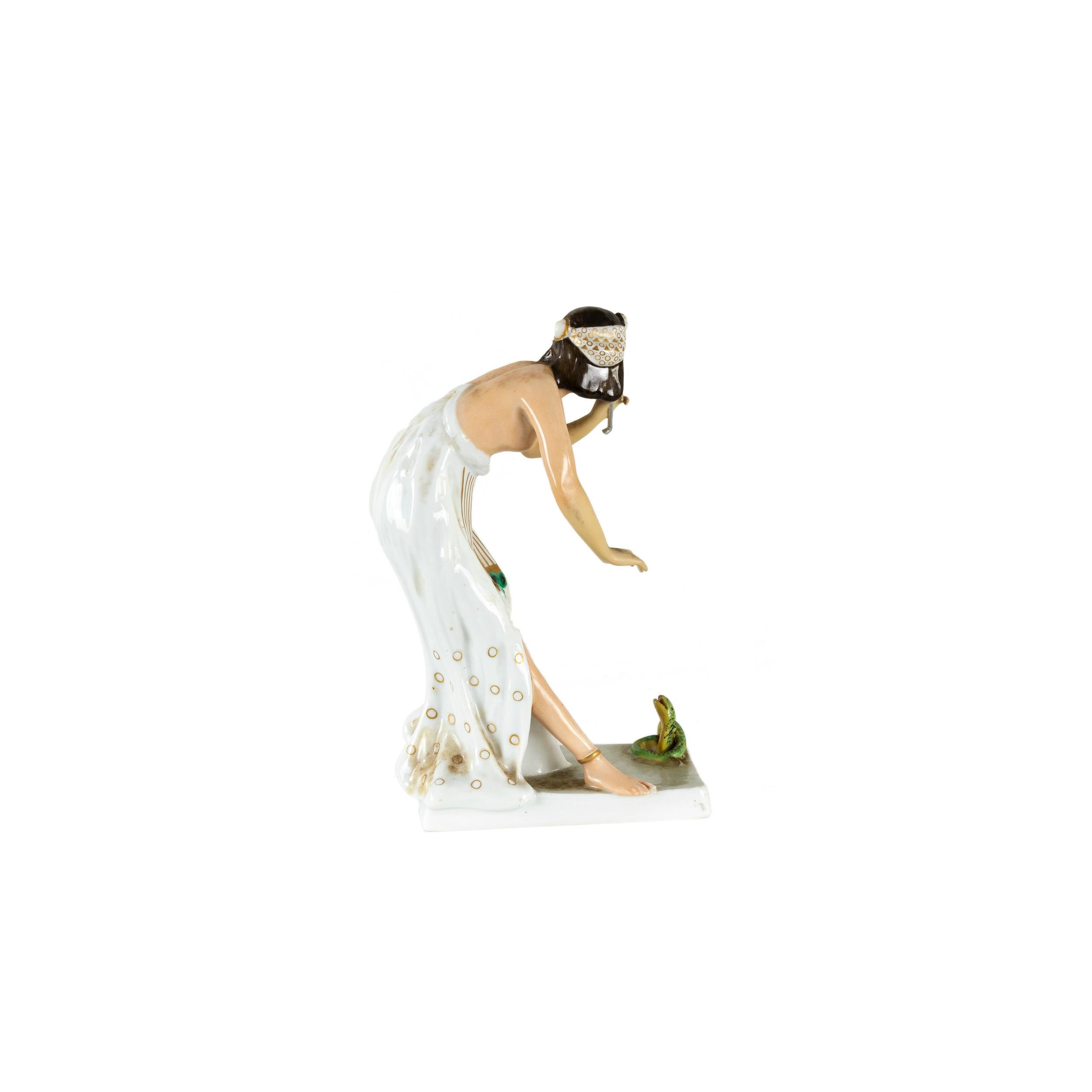 A Rosenthal porcelain figure of a snake charmer, after model by Berthold Boesz, pattern nr K442. 
Bibelot in the shape of an Egyptian-style woman, enchanting a small snake on a rectangular base.
“Philipp Rosenthal” signed and “12” mark. 
Brand