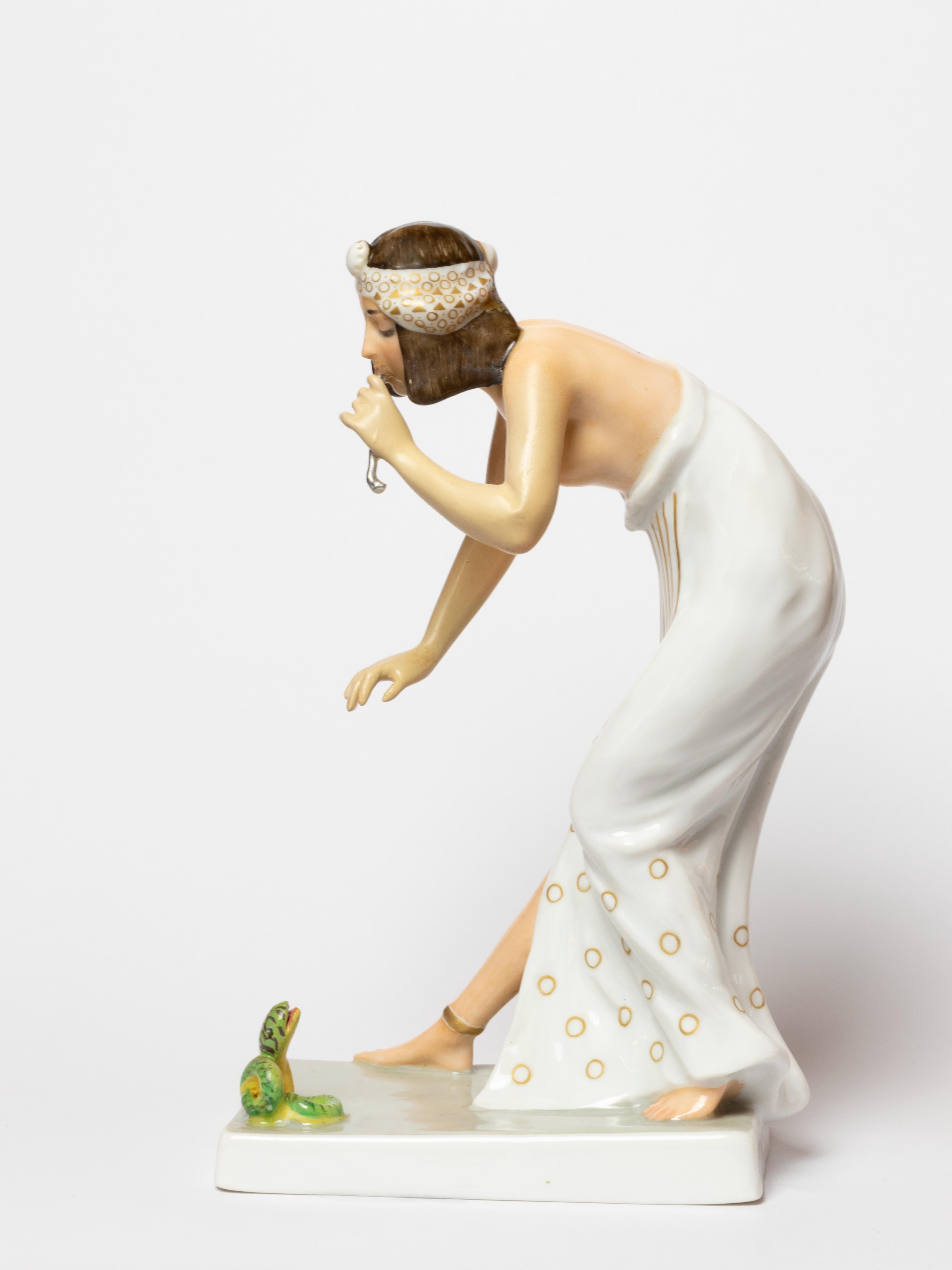 Figura di incantatore di serpenti in porcellana Rosenthal, su modello di Berthold Boesz, modello n. K442. 
Bibelot a forma di donna in stile egizio che incanta un piccolo serpente su una base rettangolare.
