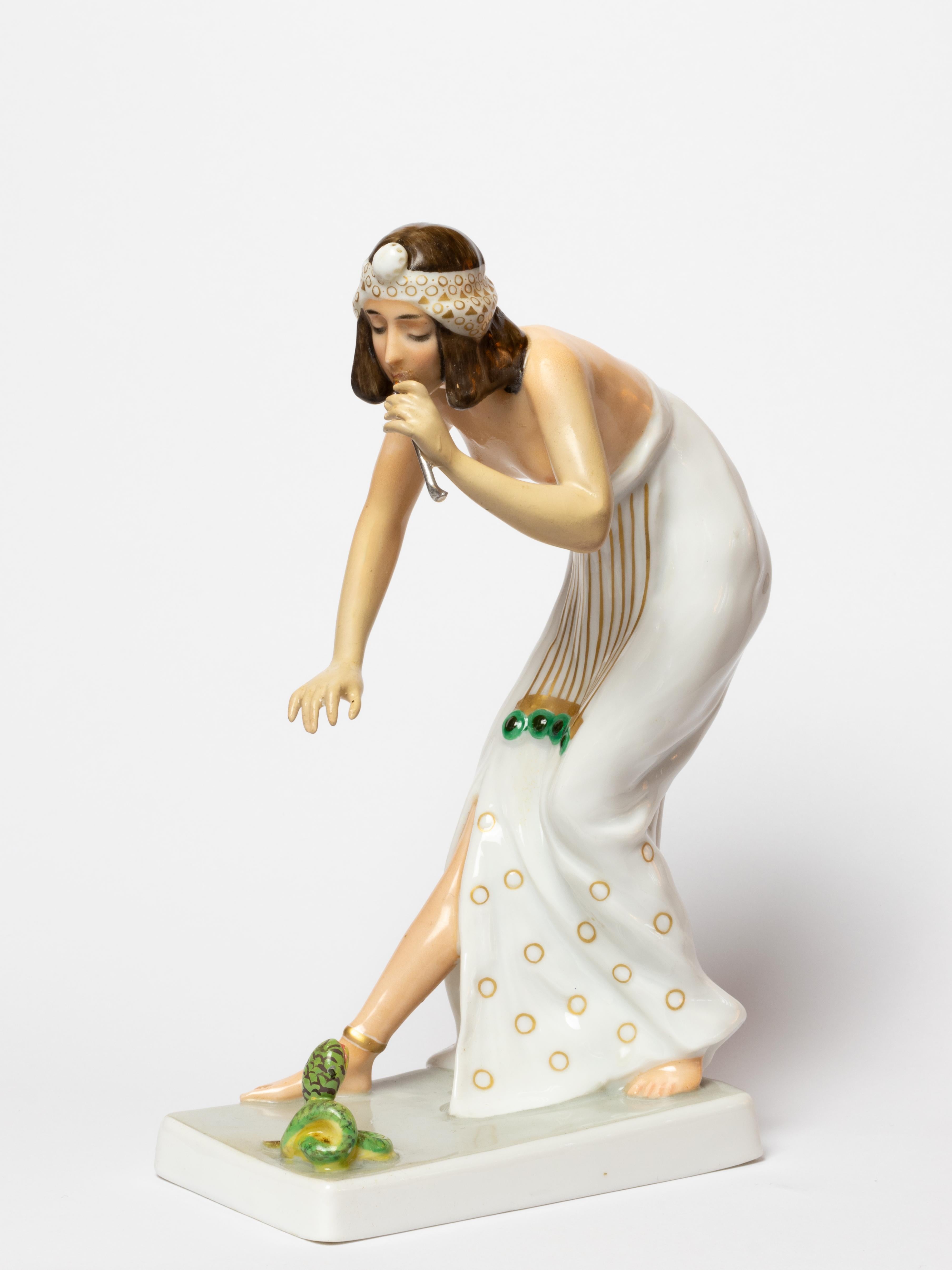 Figurine en porcelaine de Rosenthal représentant un charmeur de serpents, d'après un modèle de Berthold Boesz, modèle n° K442. 
Bibelot en forme de femme de style égyptien, enchantant un petit serpent sur une base rectangulaire.
