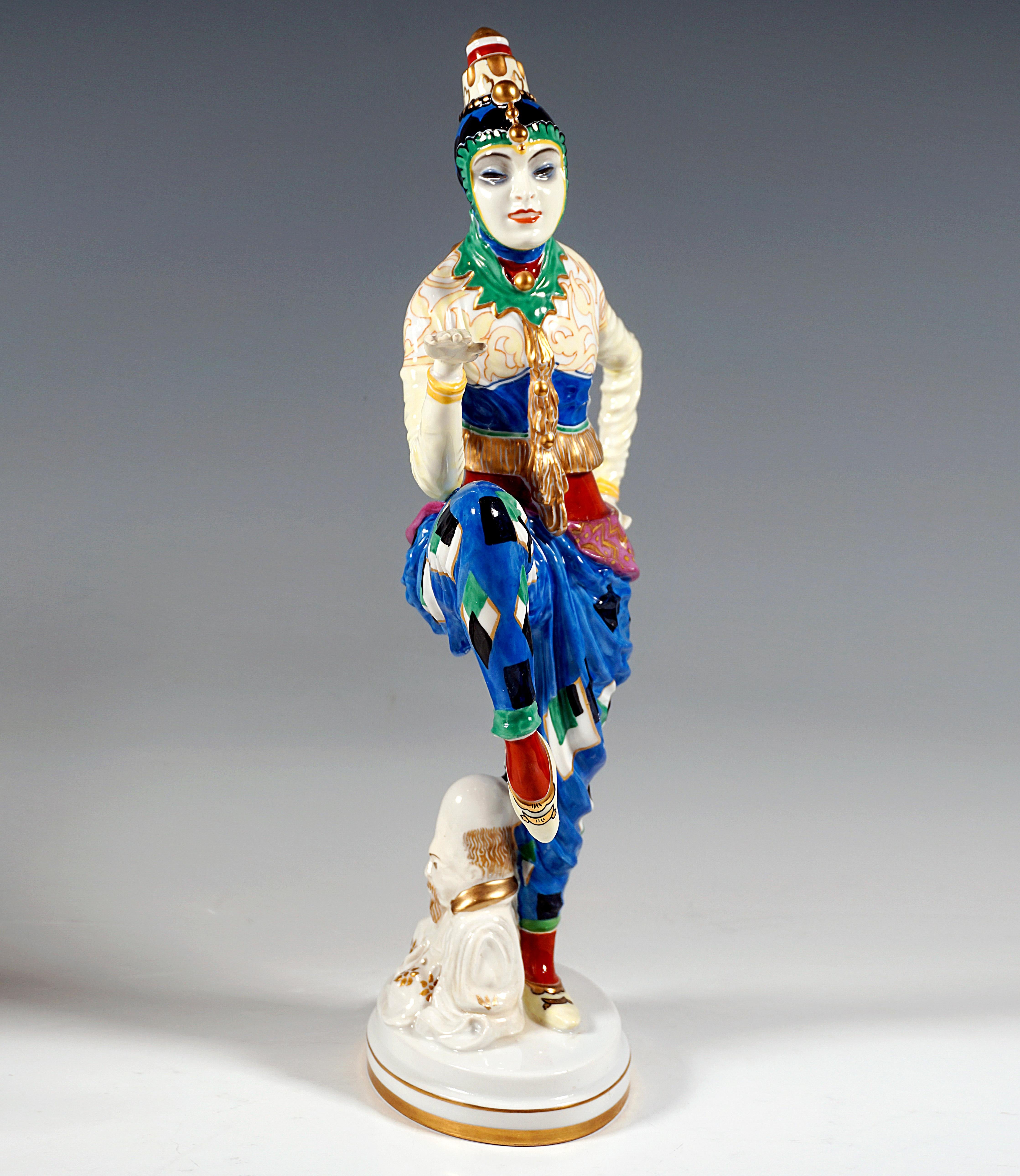 Dancer in an oriental costume with traditional Korean headgear, with raised, bent legs and arms performing a dance pose, a Chinese pagoda leaning against her leg. The figure is richly painted in bright colors and gold and is based on a white,