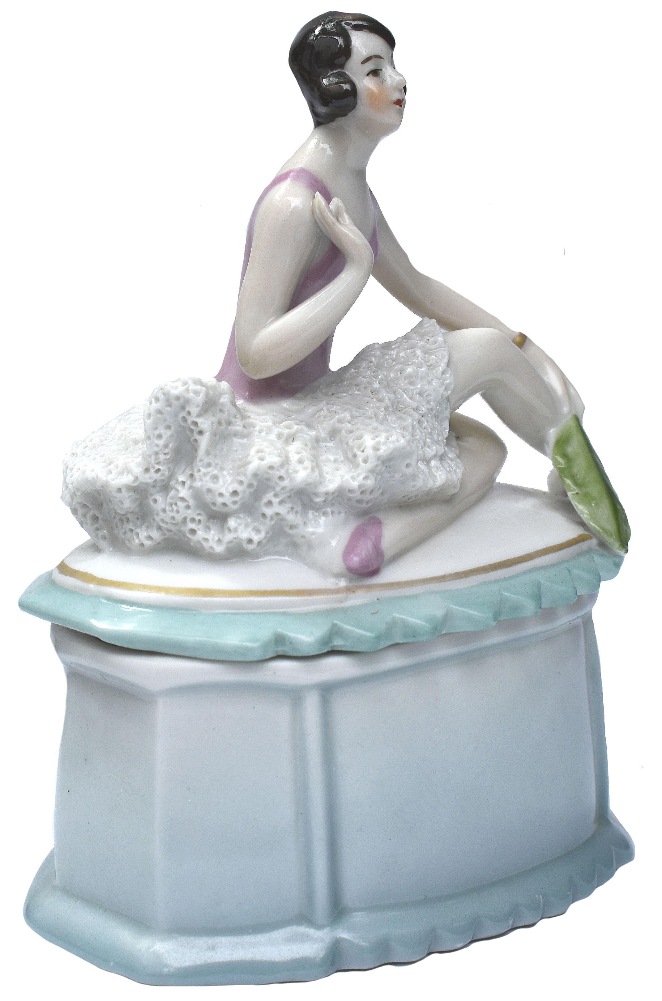 Striking and quite rare is this 1930s Art Deco ceramic powder box which depicts a stylized female dancer sat on the lid of a porcelain box. Beautiful colouring and detailing. A rare design and highly sought after. She's in great condition with no