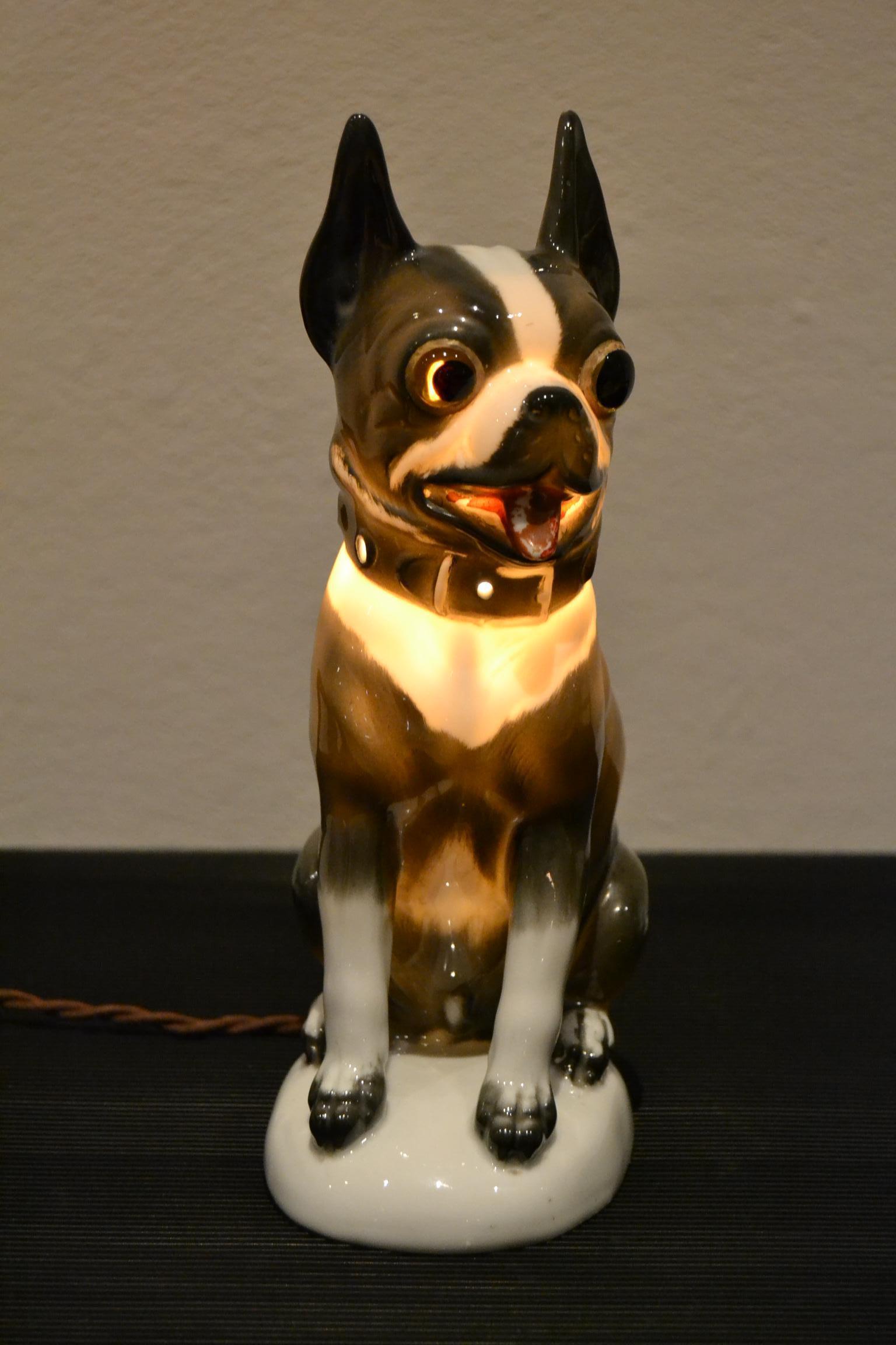 Great looking Frenchie - Boston terrier perfume lamp.
This large figural perfume light dates from the 1930s.
Art Deco porcelain animal light - table lamp in the shape of a cute looking dog statue:
A French bulldog - Boston Terrier with big glass