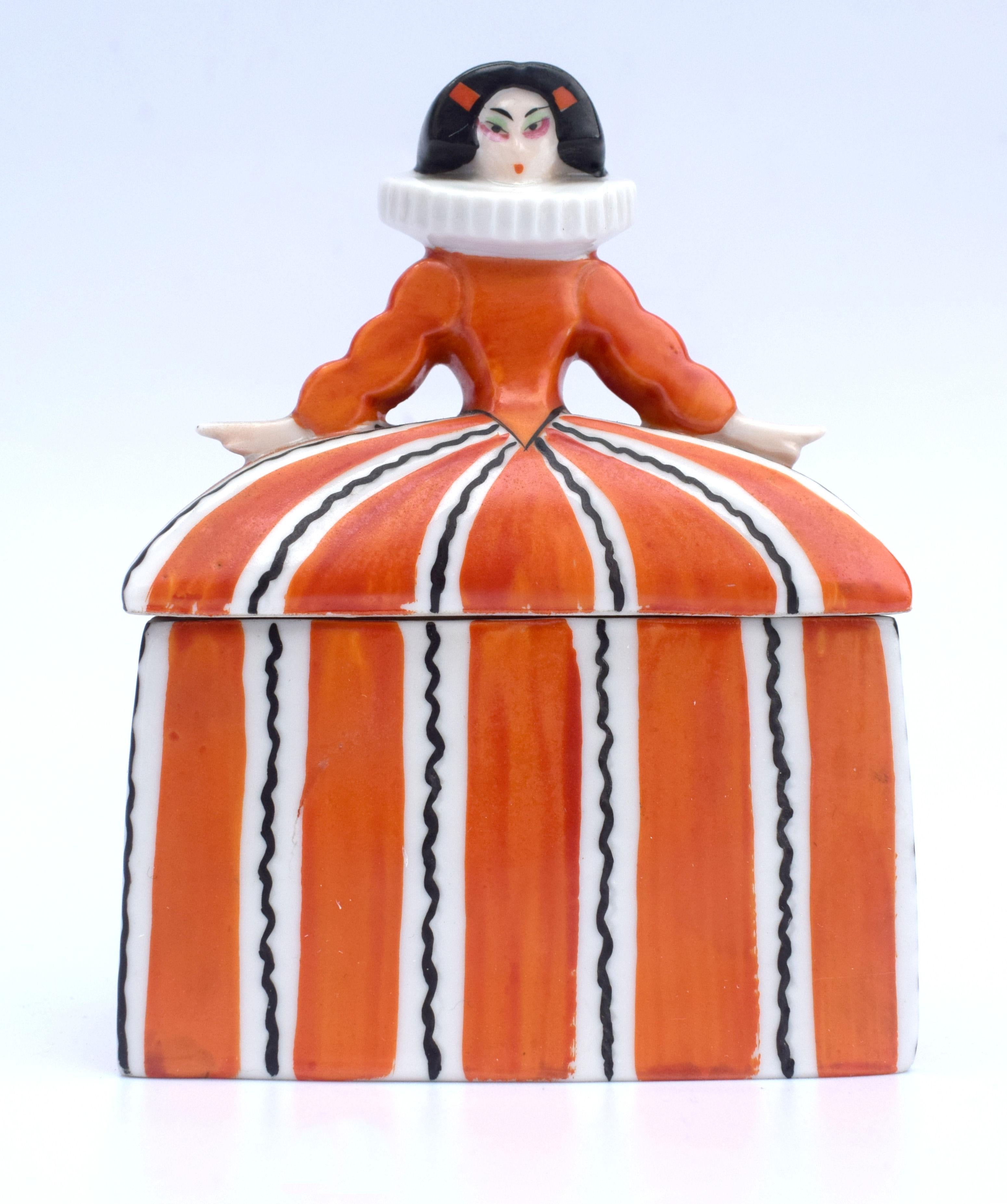Possibly one of our all time favourite Art Deco powder bowls is this fine porcelain example, dating to the 1930s and originating from Germany made by Wallendorf Thuringia company. This highly stylized lady is painted in vivid orange and black on the