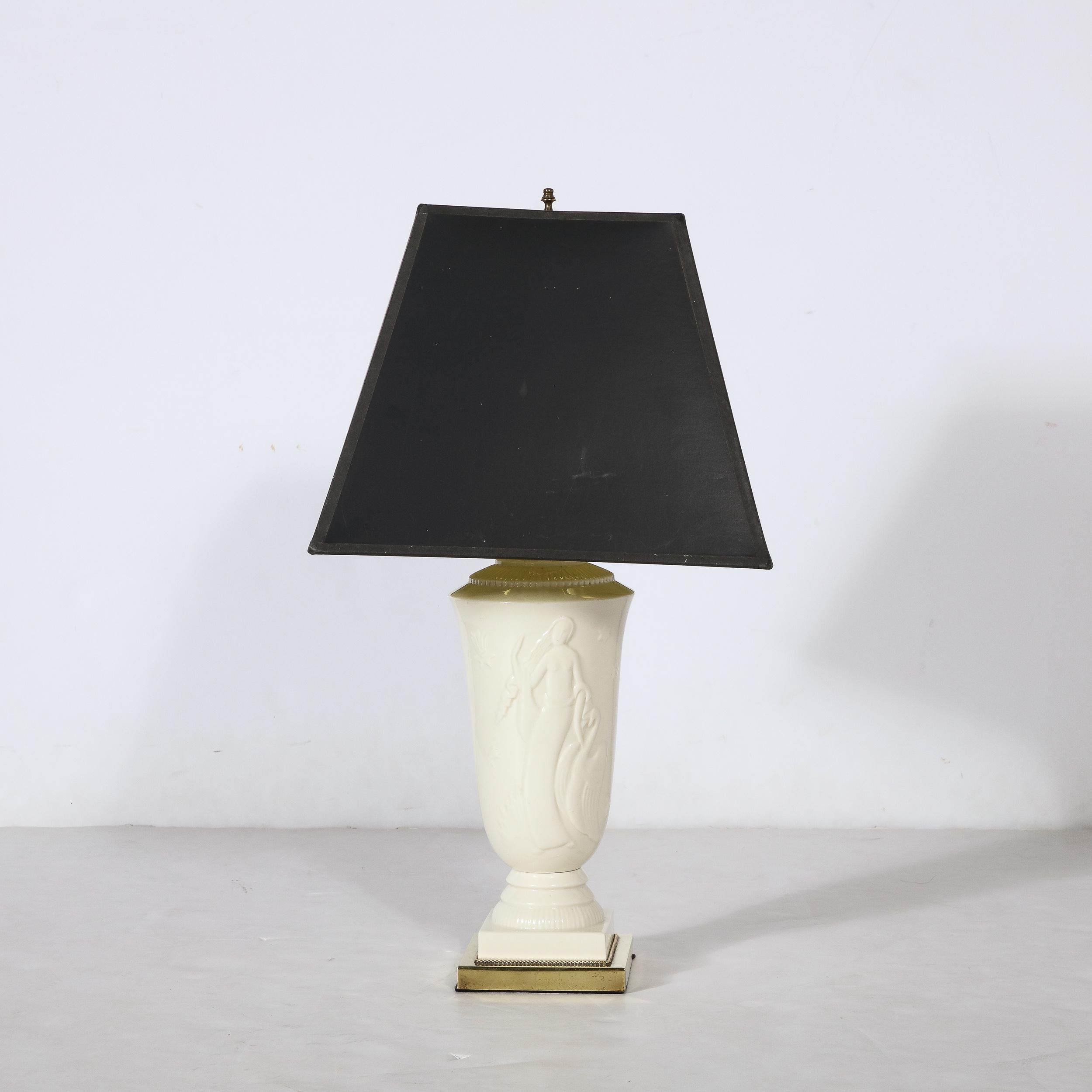 Diese schöne Art Deco Porzellan Tischlampe von Leda und dem Schwan von De Vegh für Lenox stammt aus den Vereinigten Staaten, CIRCA 1930. Mit einem rechteckigen Sockel aus poliertem Messing, aus dem sich der urnenförmige Lampenkörper erhebt. Das