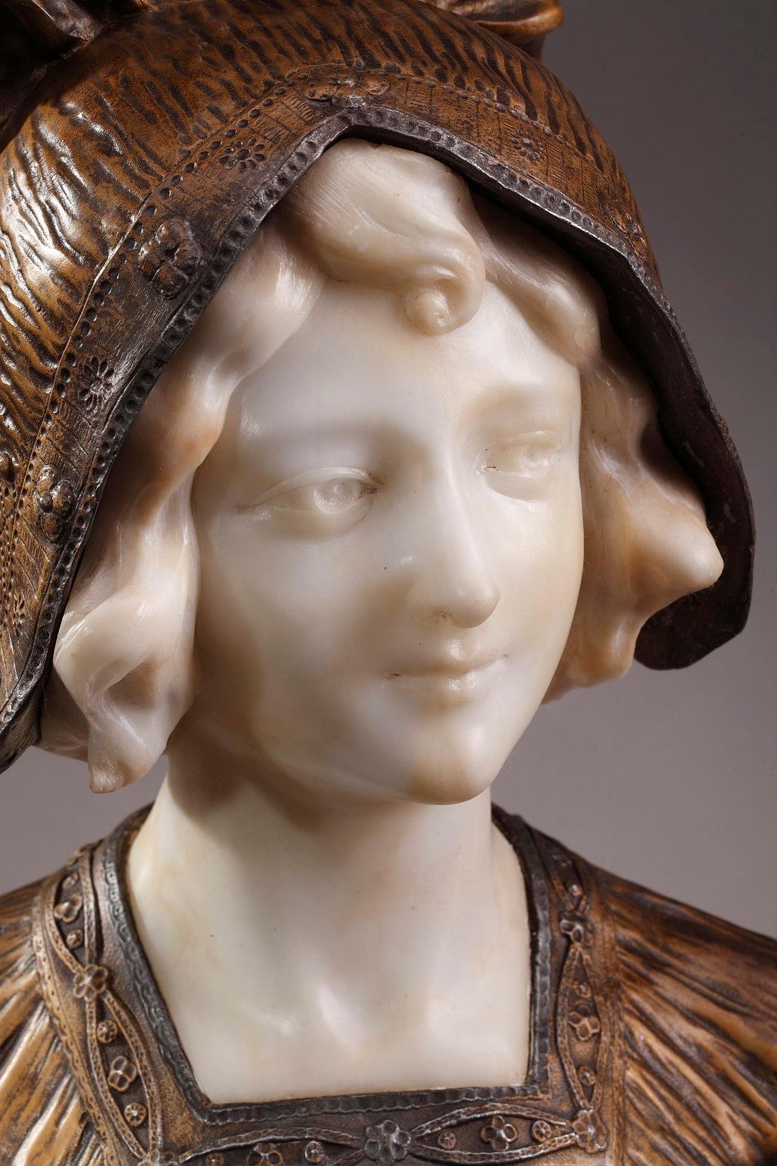 Buste portrait Art Déco du début du 20ème siècle finement ouvragé en métal doré et albâtre représentant une jeune femme. Elle porte un élégant couvre-chef brodé de fleurs et un châle. La tête en albâtre repose sur une base en marbre rouge. Signé A.