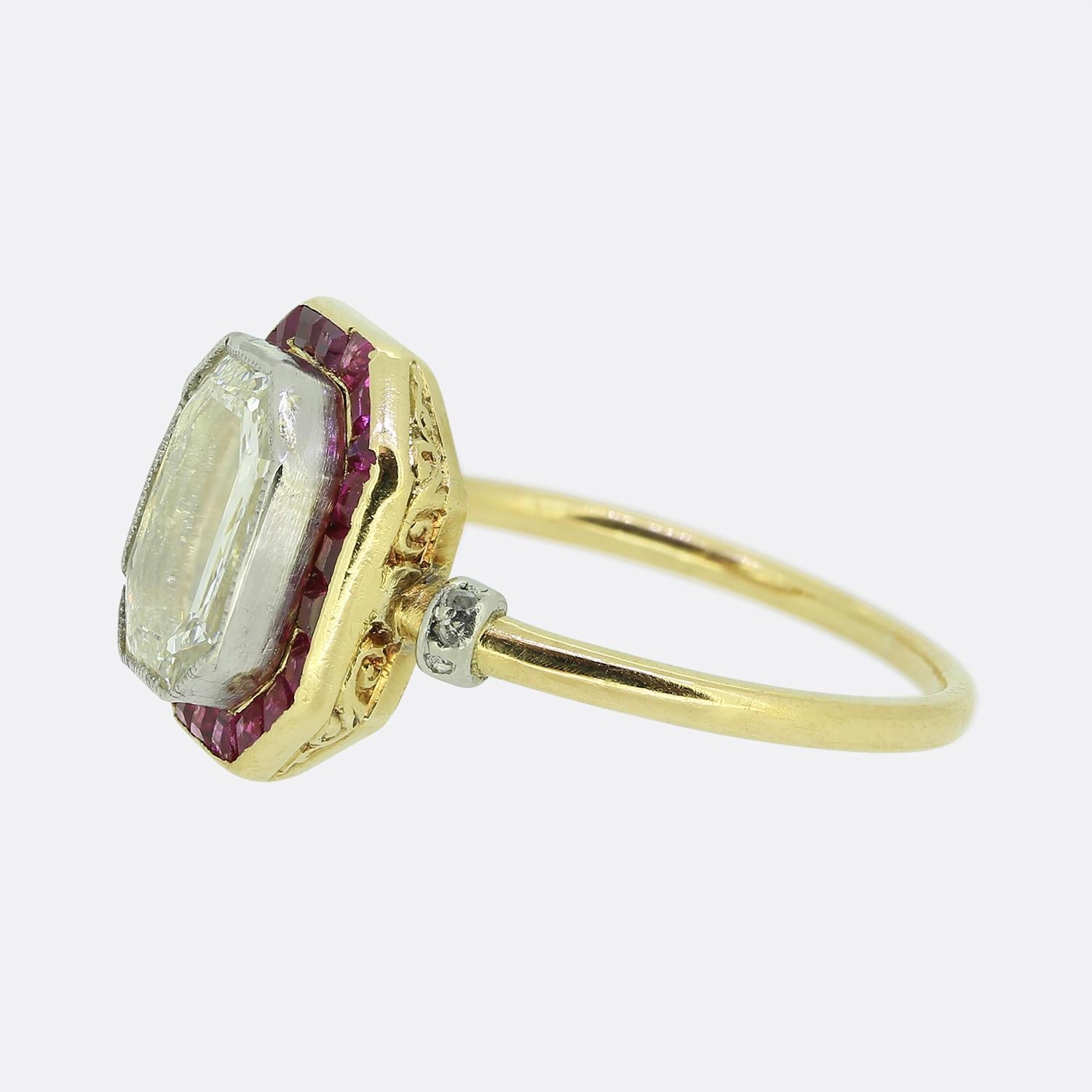 Here we have an exquisite Art Deco ring. This early 20th-century piece showcases a striking portrait-cut white diamond at the centre. This clean diamond sits in a fine milgrain setting before being framed by a vivid frame of square-cut red rubies,