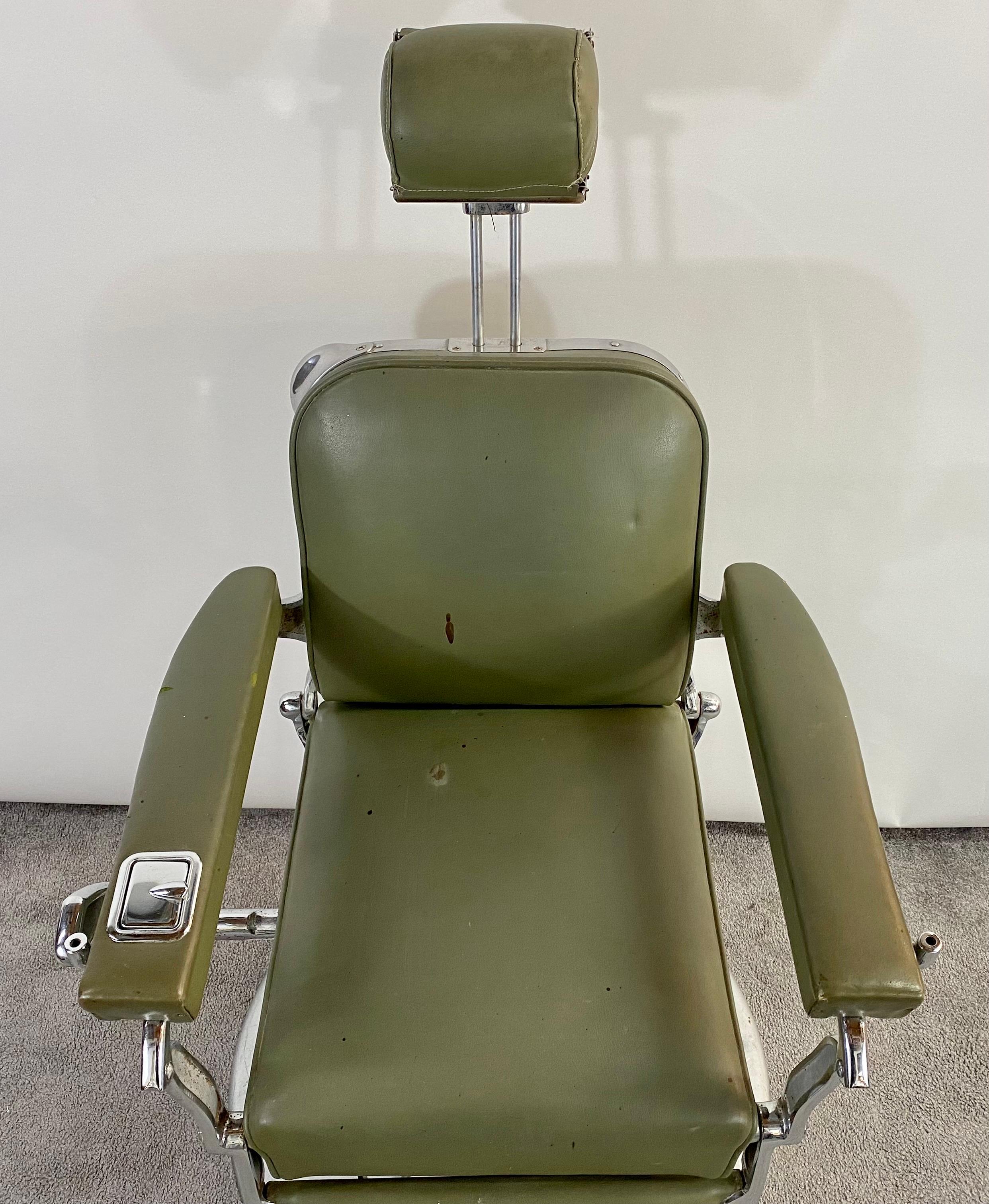 A vintage Art Deco 1930's Koken Barber chair in green leather with head rest. This chair is an exceptional collector item. The chair is made by Koken manufacturing & Co of St Louis, Missouri and ithe foot plate 
